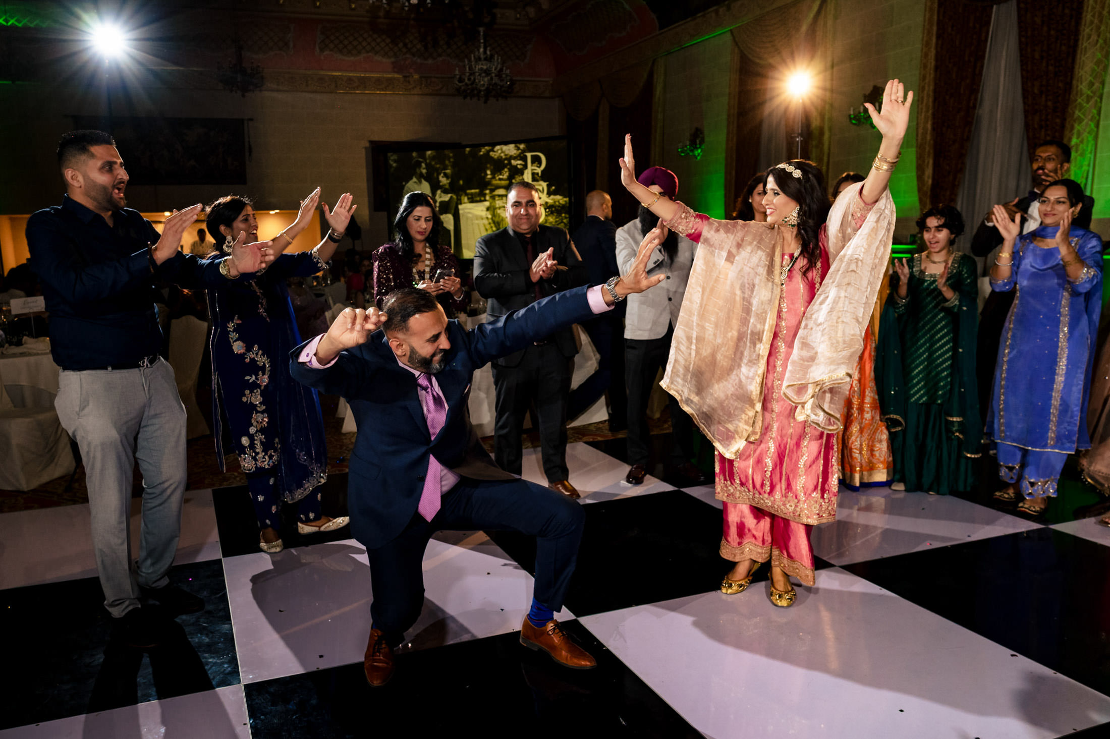 Guests dance energetically on a checkered floor at a lively Winnipeg wedding.
