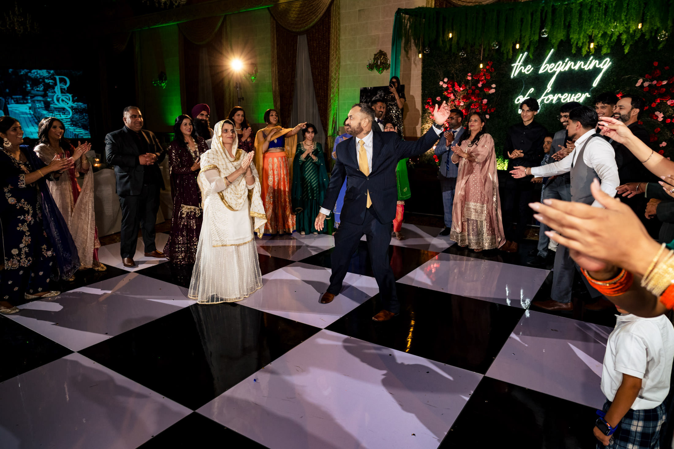 Couple dancing at their Winnipeg wedding, guests cheering on a checkerboard floor.