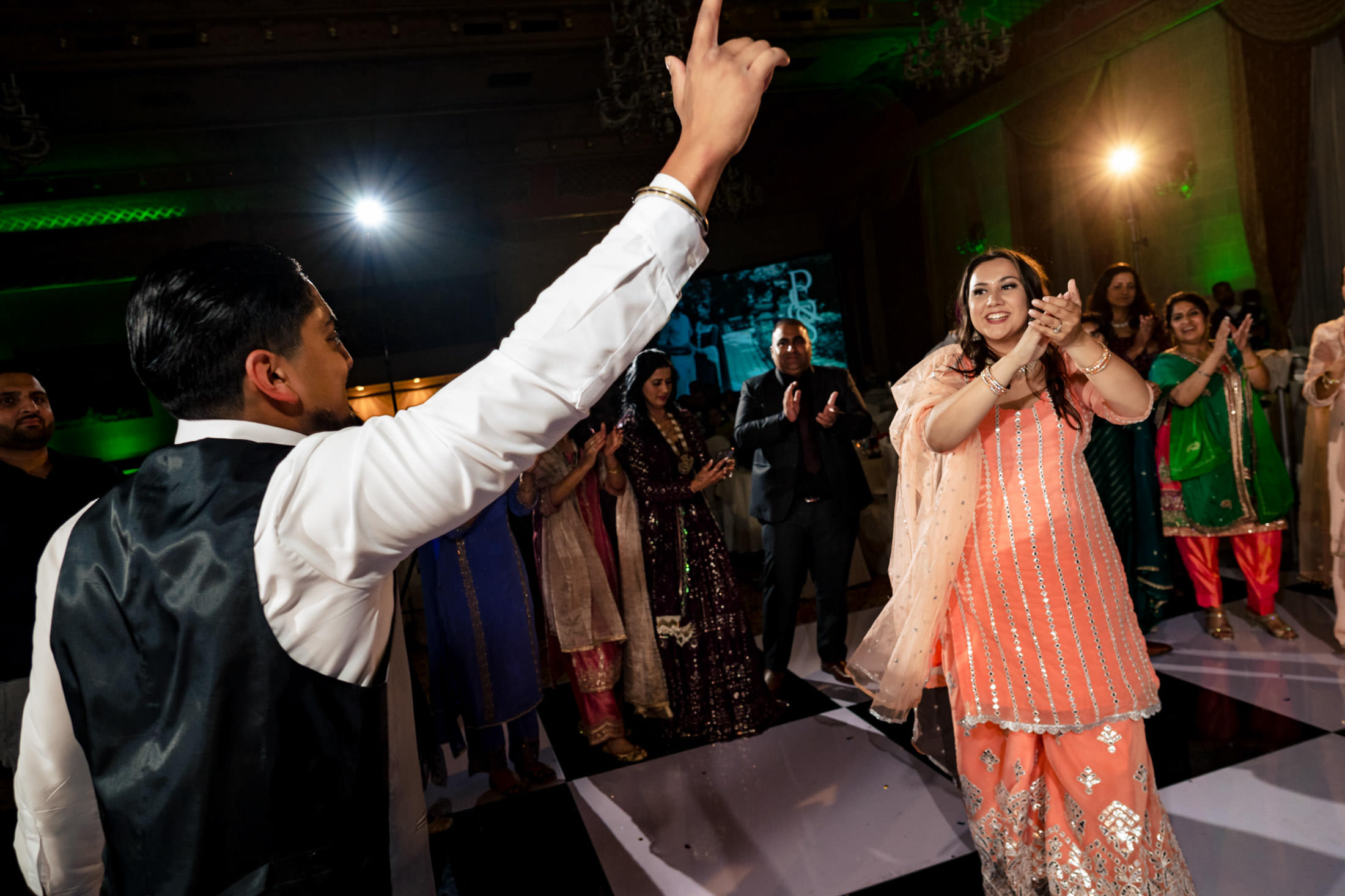 A couple dances joyfully at a lively Winnipeg wedding, surrounded by cheering guests.