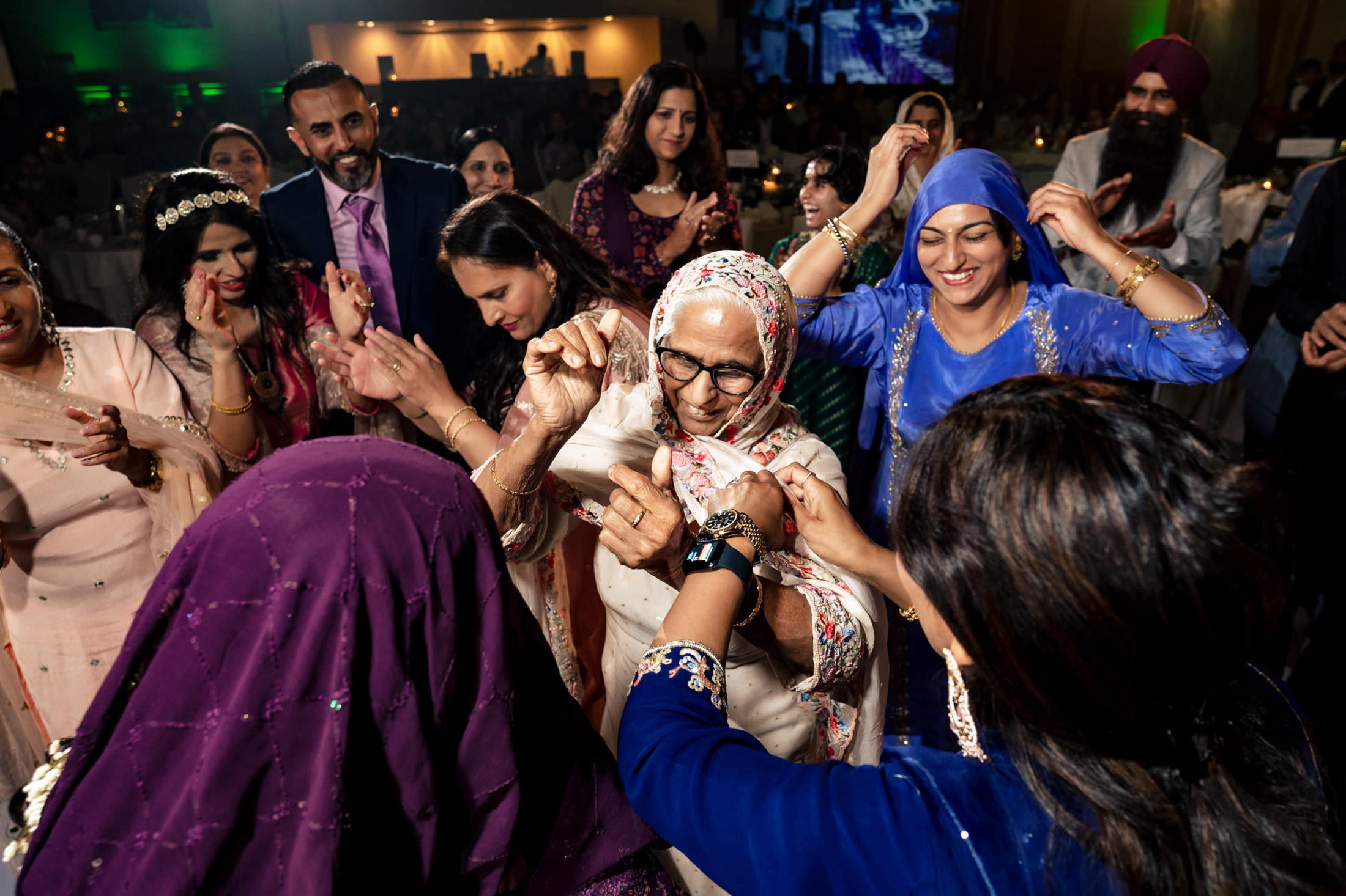 People joyfully dancing at a Winnipeg wedding, dressed in colorful traditional clothing.