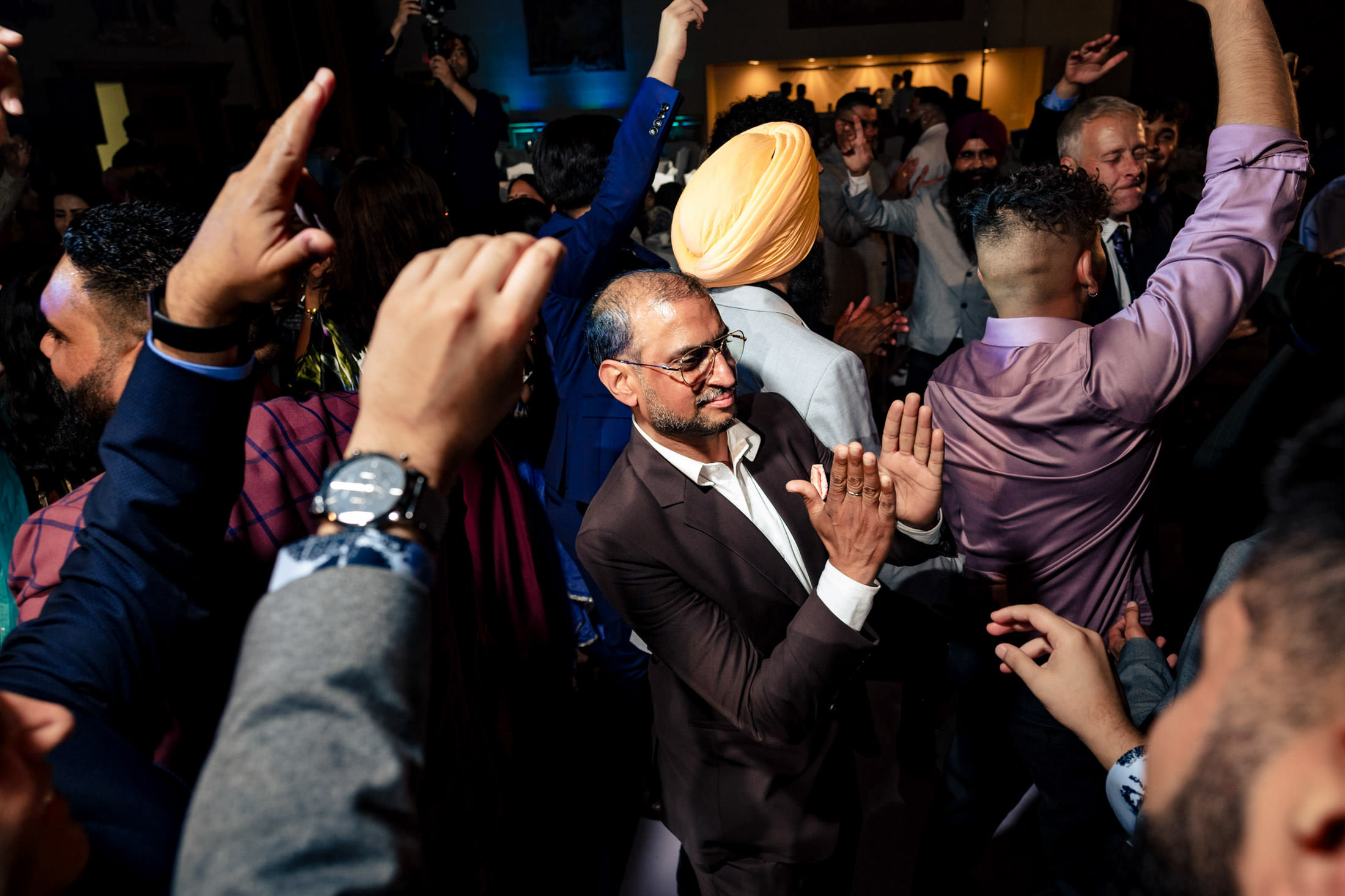 Energetic dancing at a Winnipeg wedding, hands raised and smiling faces all around.