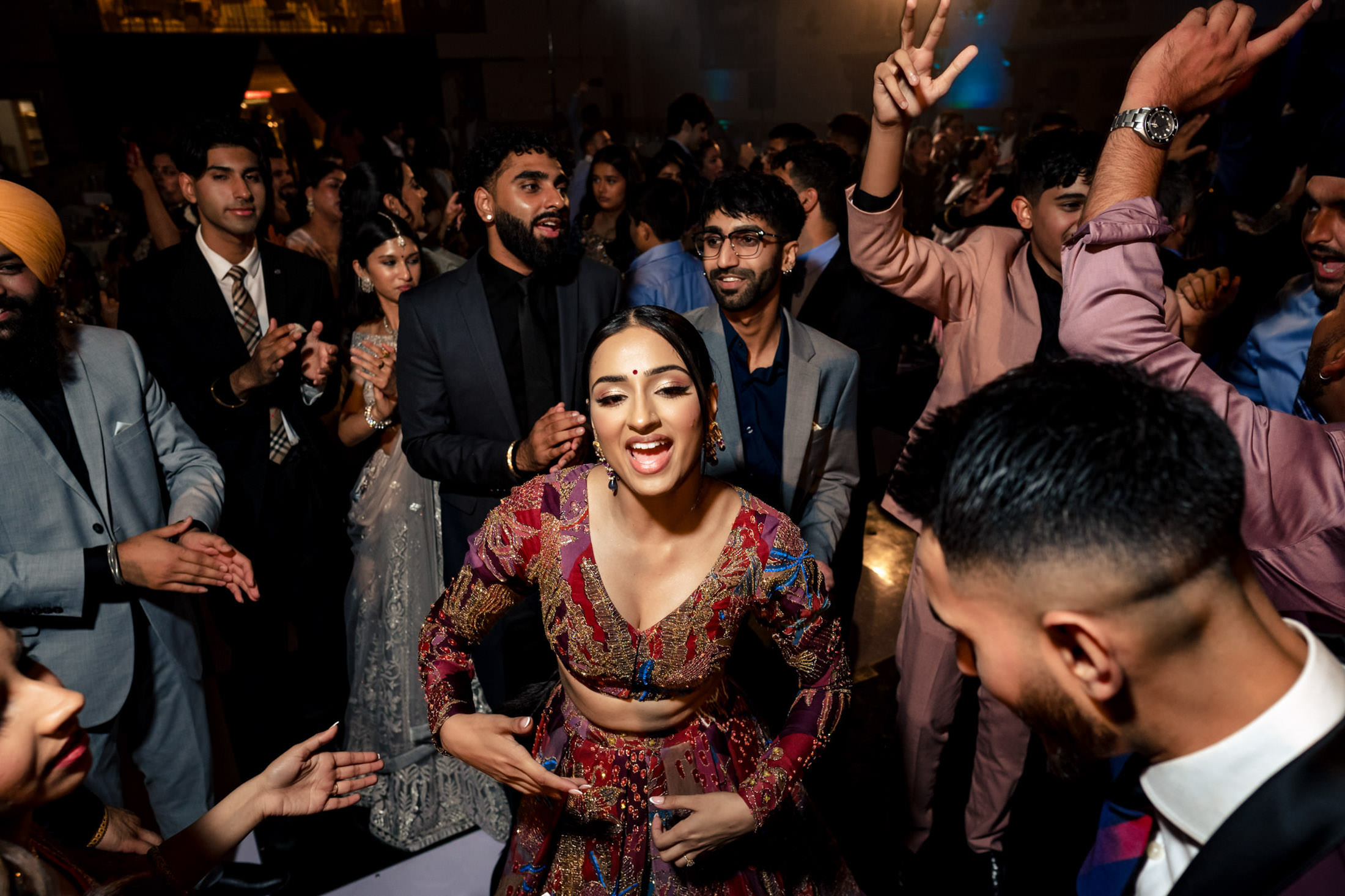 A woman in colorful attire dances joyfully at a lively Winnipeg wedding.