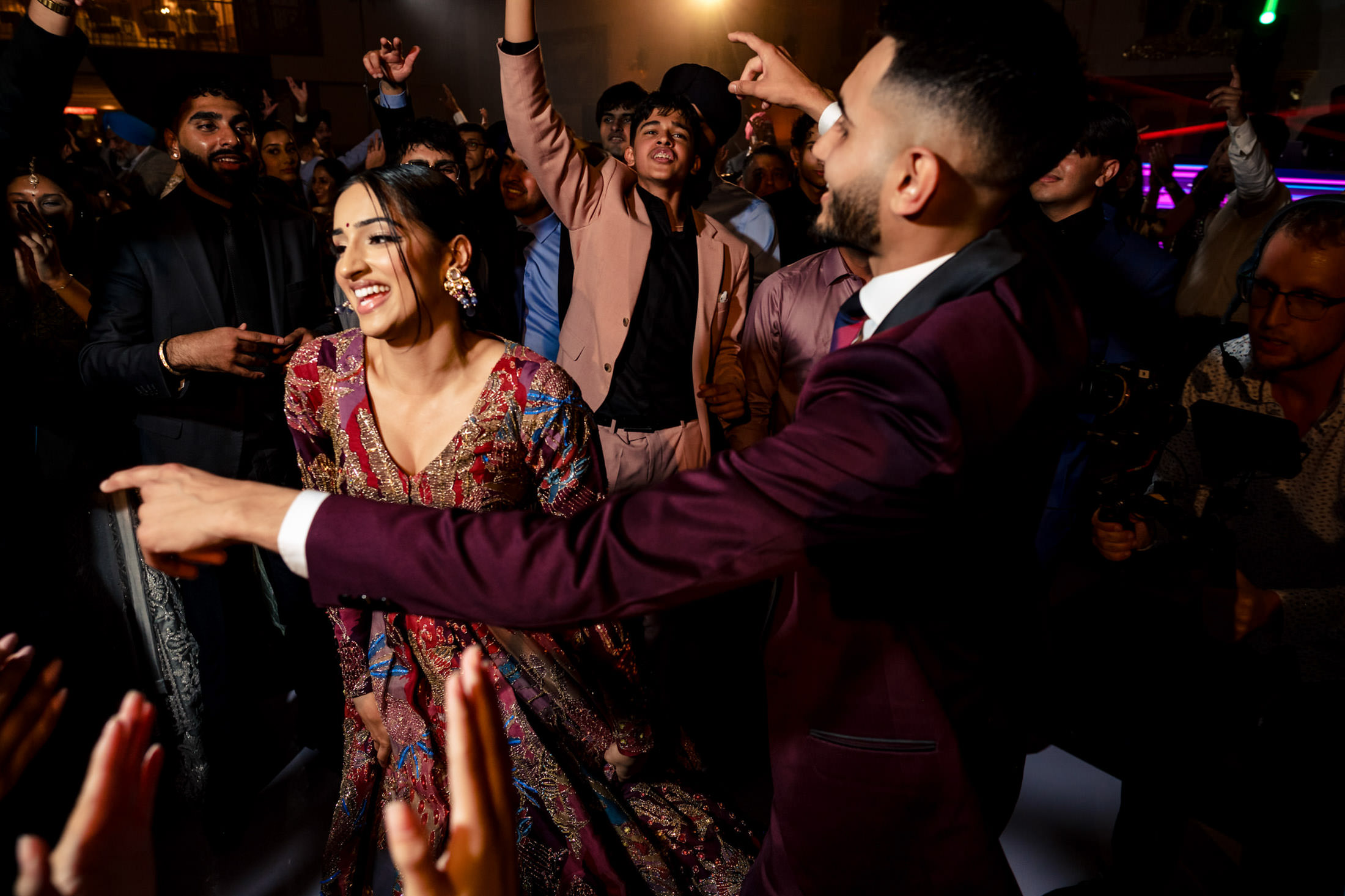 People dancing joyfully at a lively Winnipeg wedding, dressed in vibrant attire.
