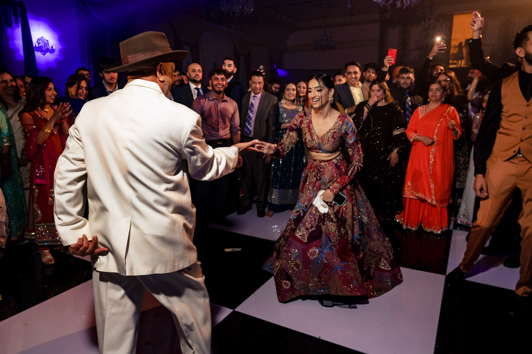 A man and woman joyfully dancing at a lively Winnipeg wedding with a cheering crowd.