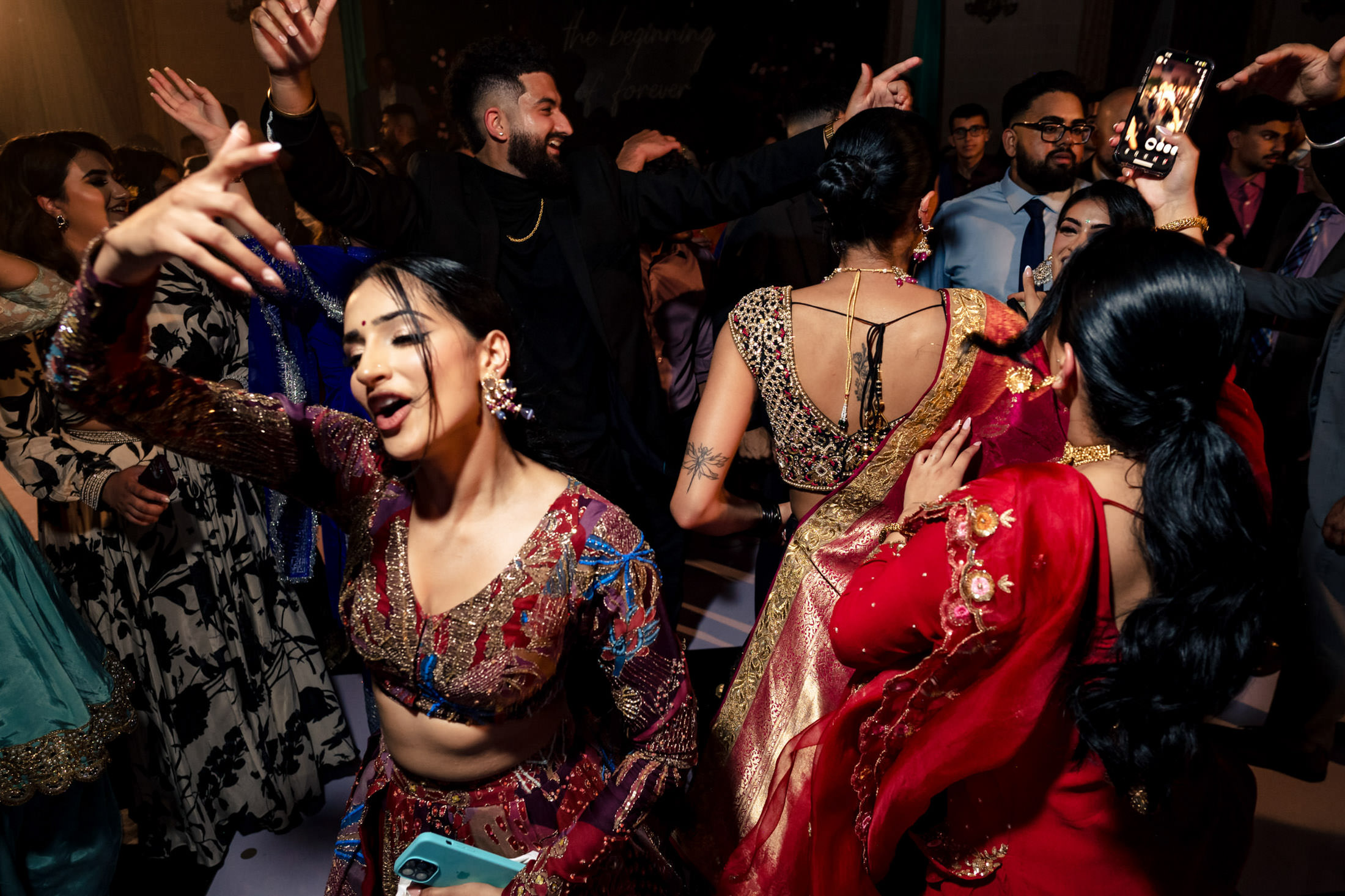 People dancing energetically at a Winnipeg wedding, wearing colorful traditional outfits.
