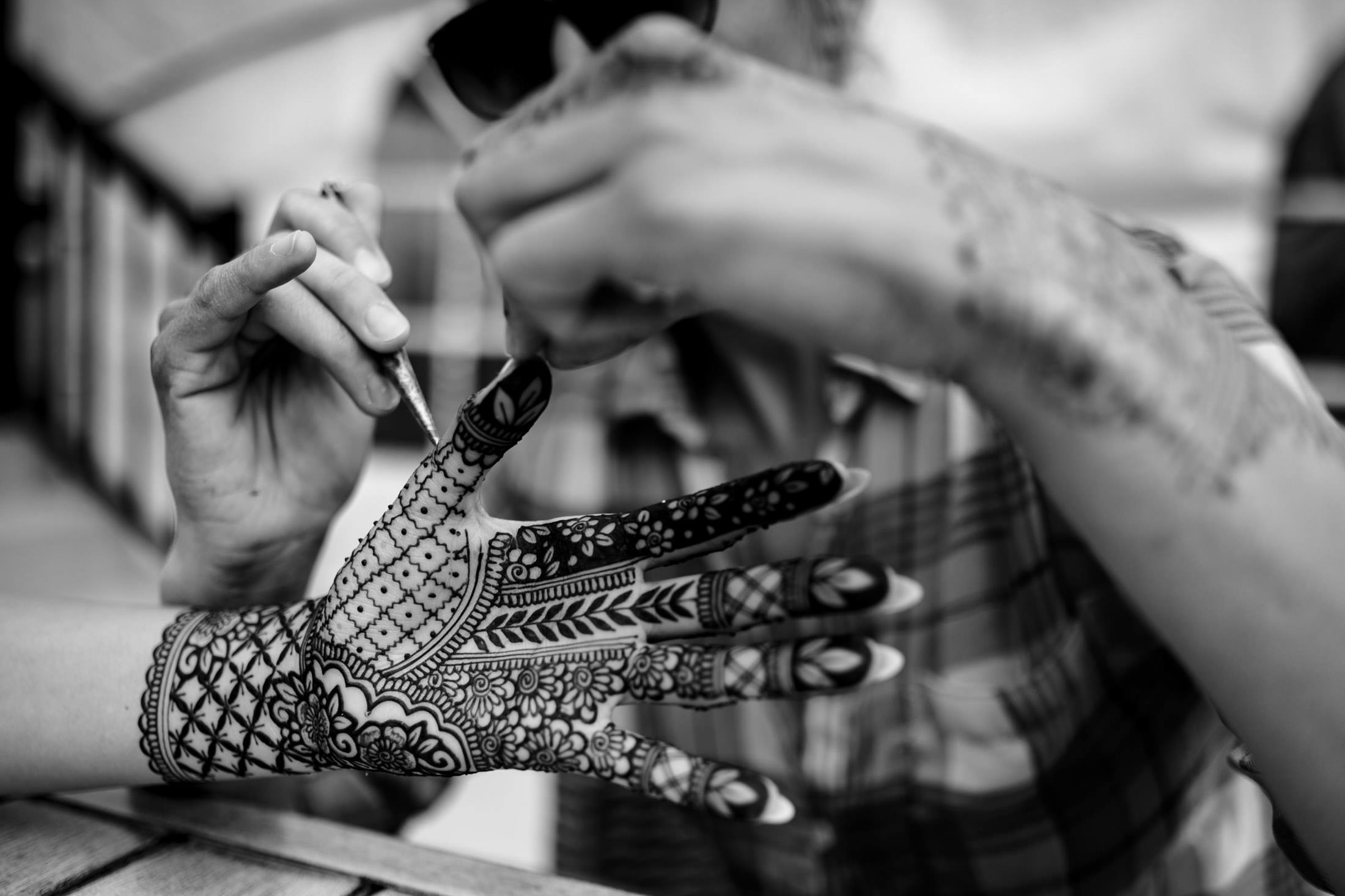 A person intricately applies henna designs at a Winnipeg wedding.