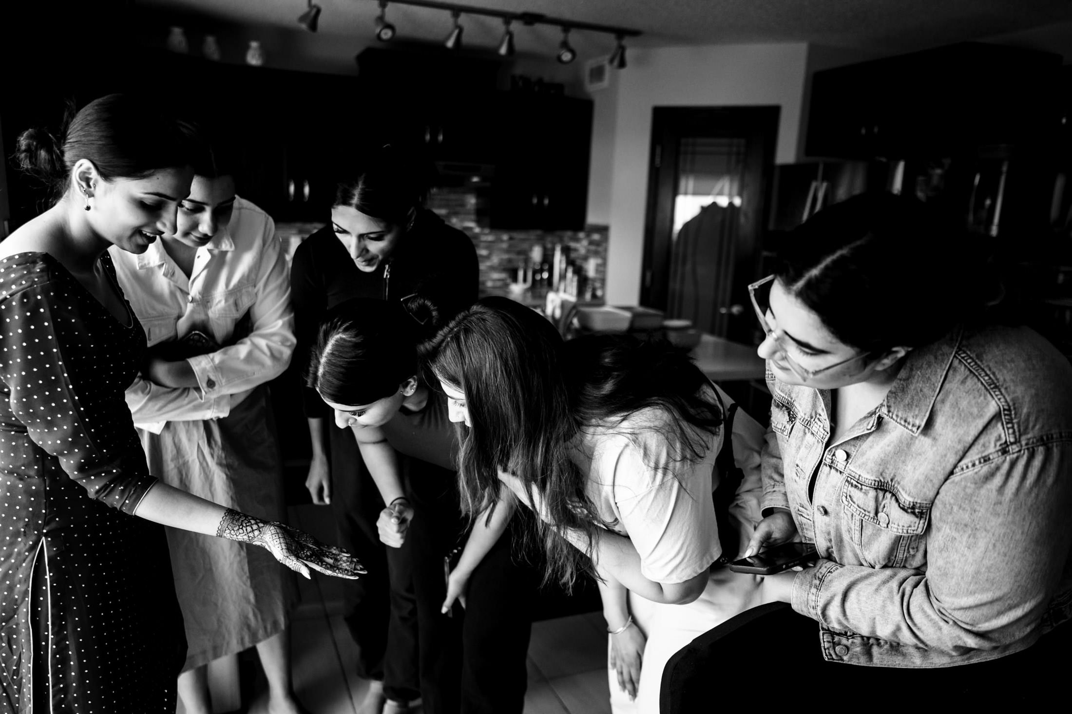 Group admires henna on a woman’s hand in a Winnipeg wedding kitchen.
