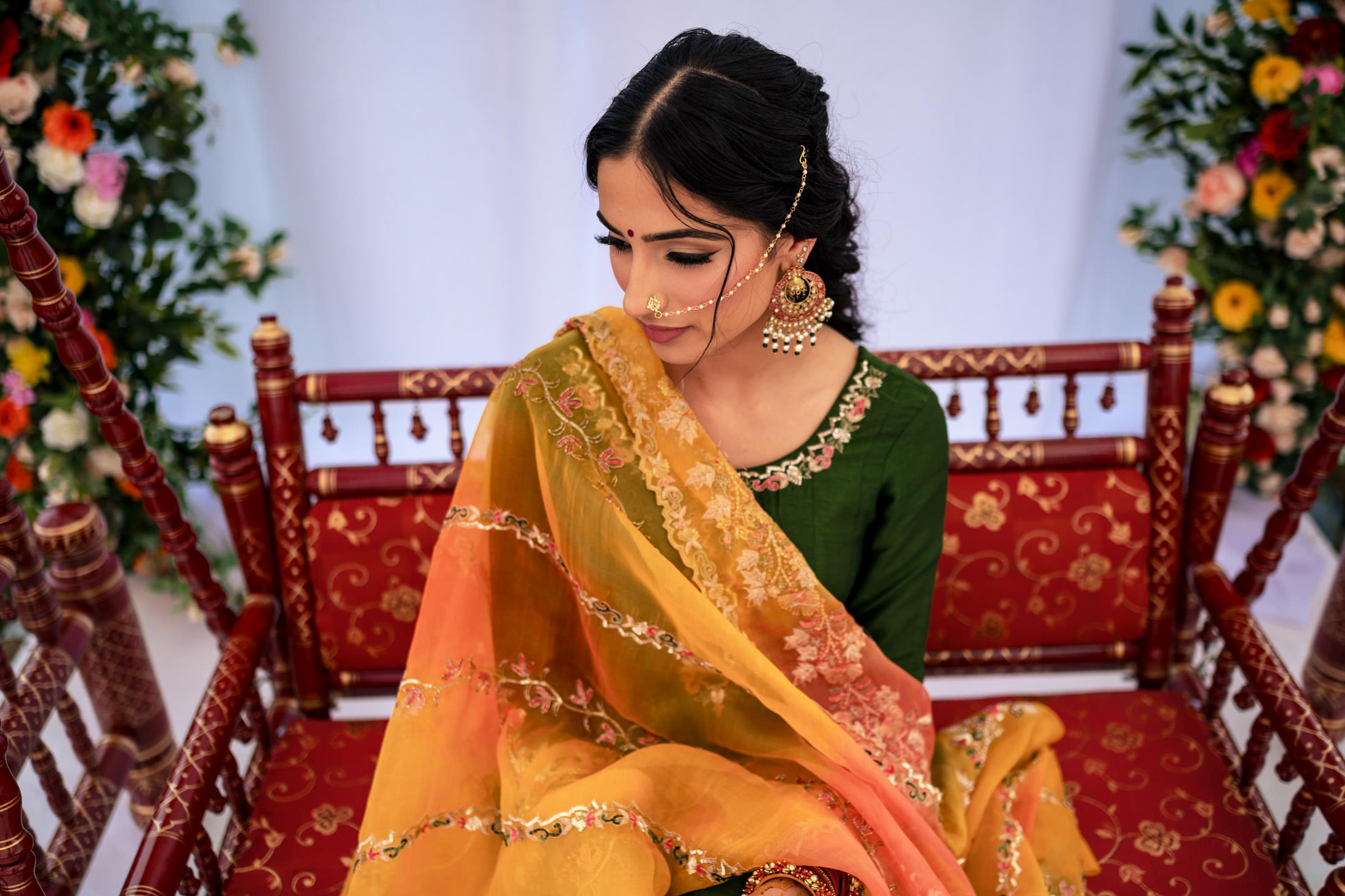 Woman in traditional attire on an ornate chair, surrounded by Winnipeg wedding florals.