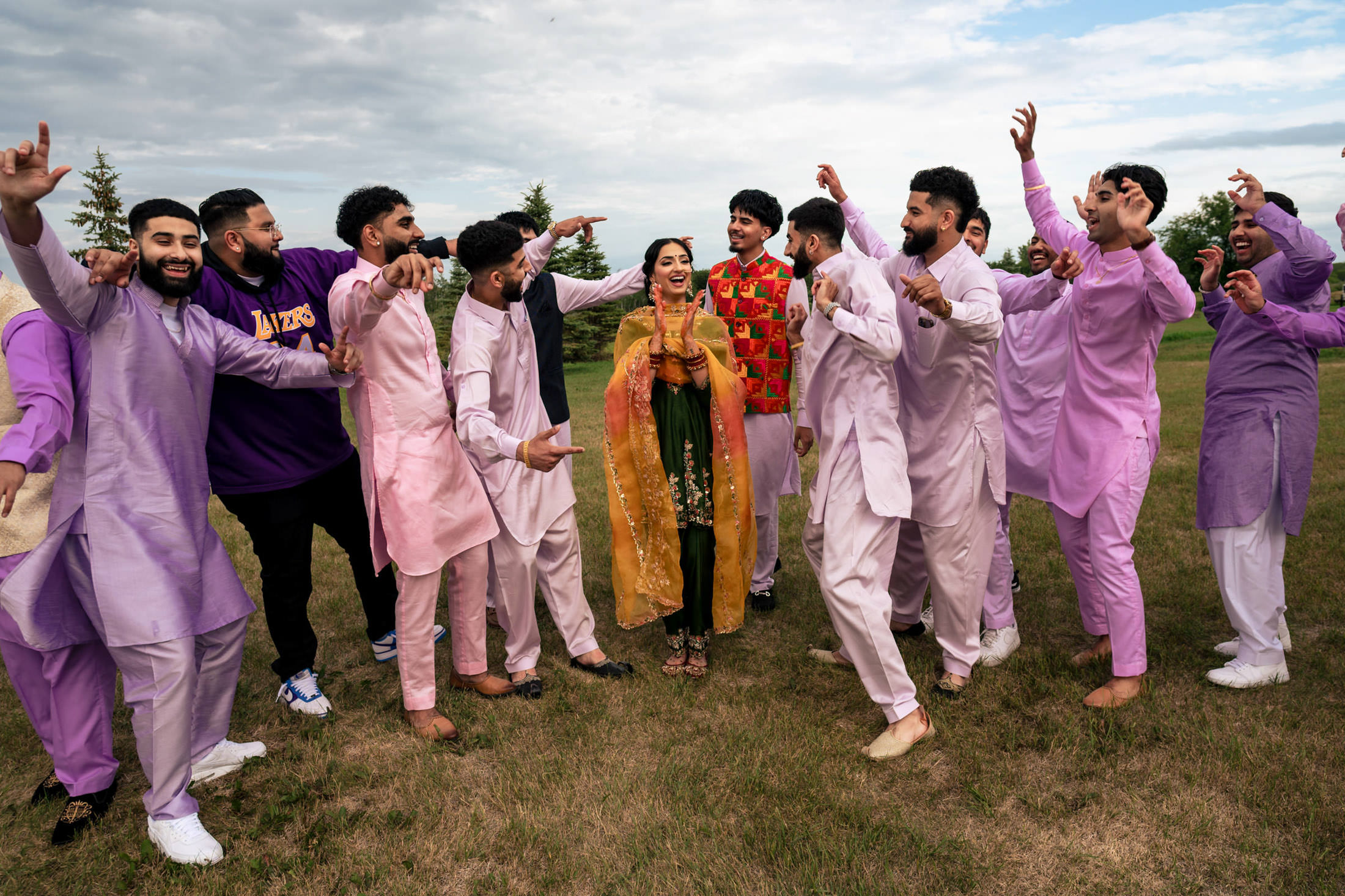 A joyful group celebrates a Winnipeg wedding in colorful traditional attire outdoors.