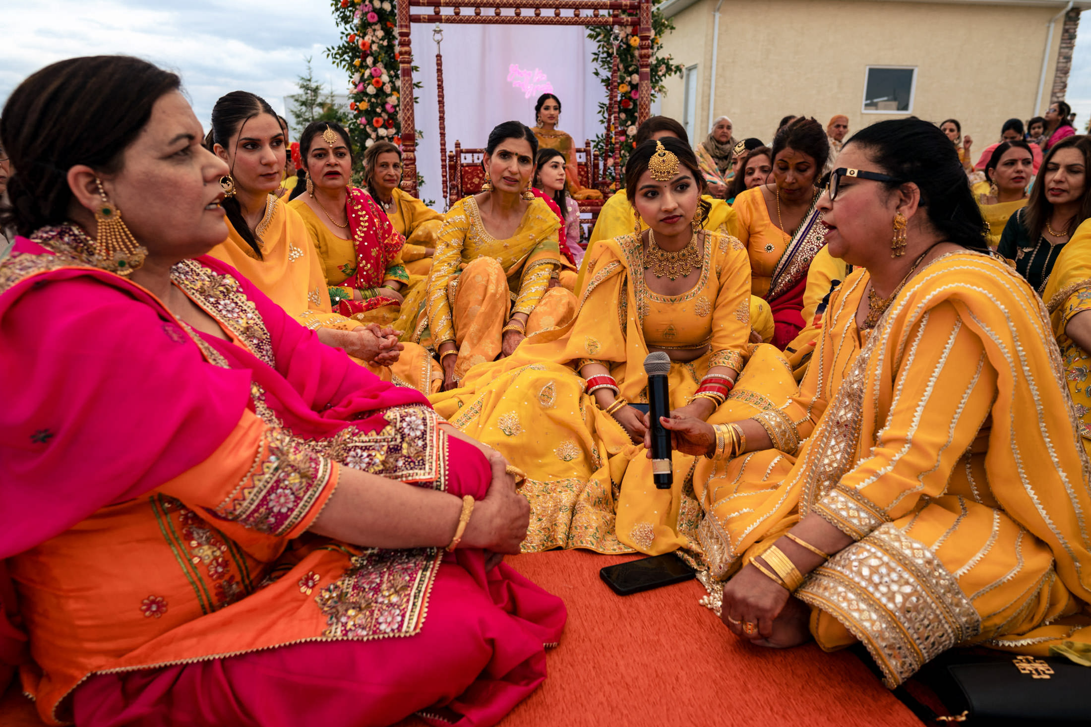 Women in colorful traditional attire at a vibrant Winnipeg wedding, seated in a group.