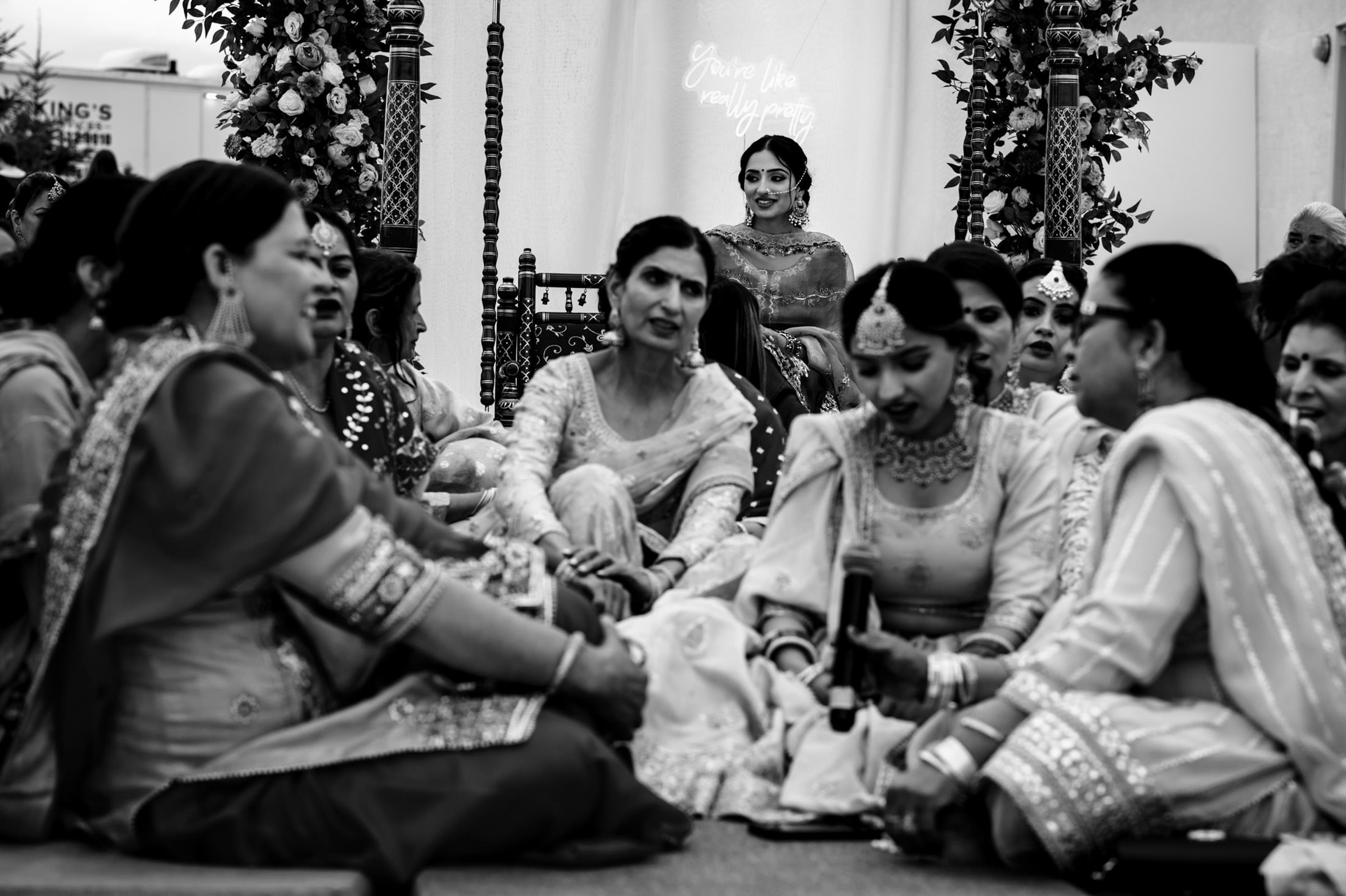 Bride sits behind a group of women at a Winnipeg wedding in black and white.