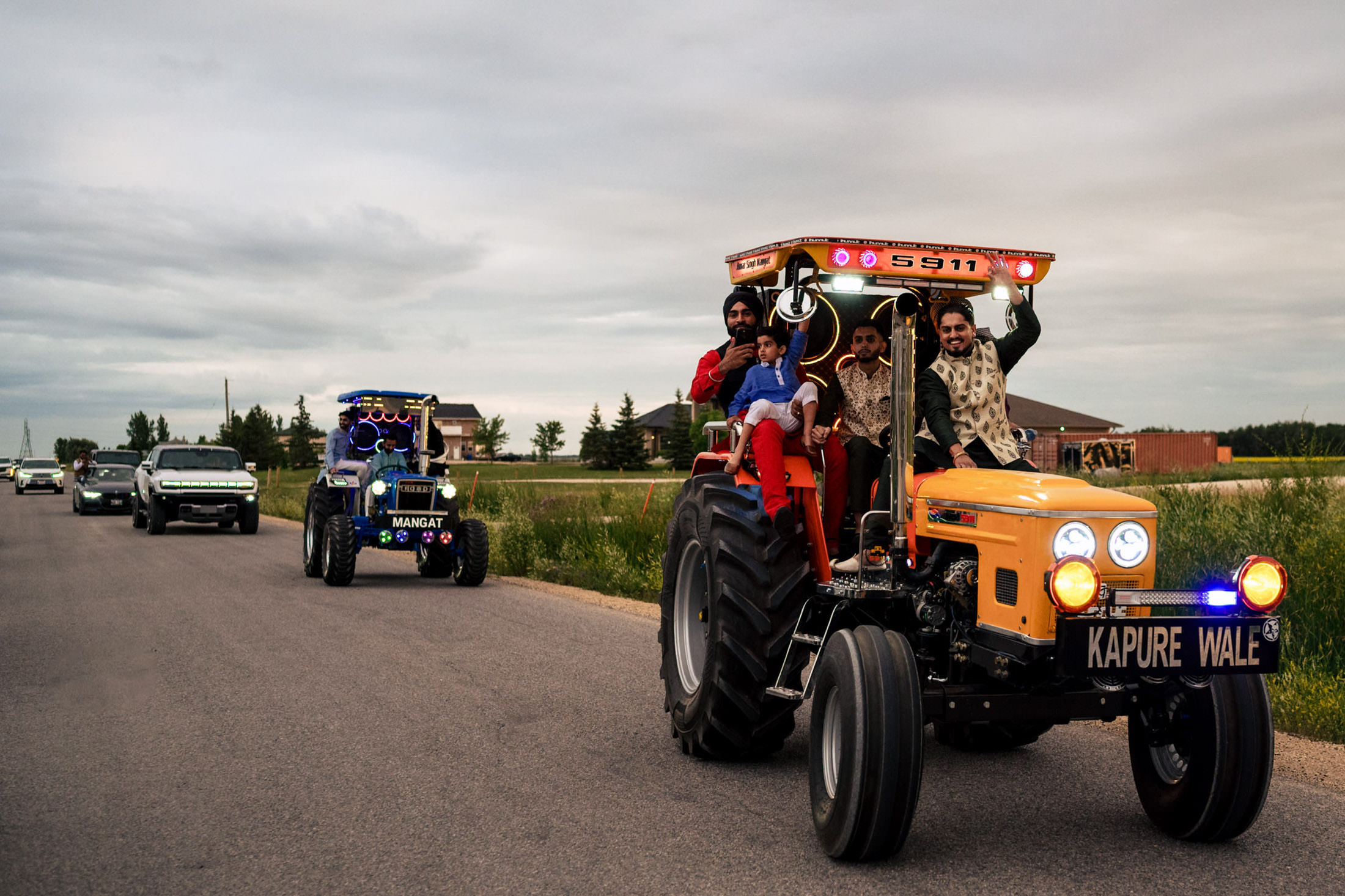 People riding on colorful tractors in a road parade, like a Winnipeg wedding celebration.