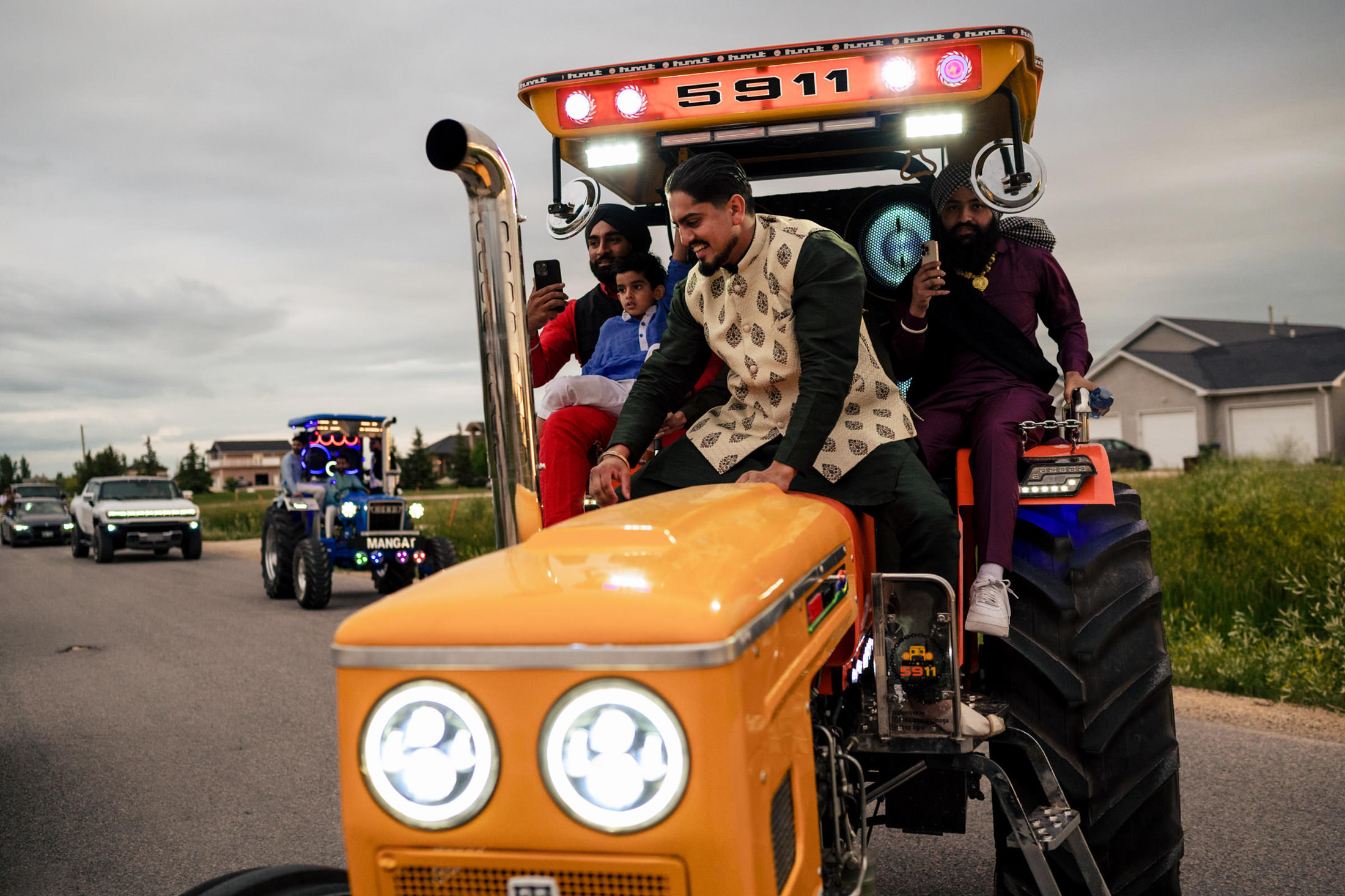 A group celebrates a Winnipeg wedding, riding tractors with two in vibrant traditional attire.