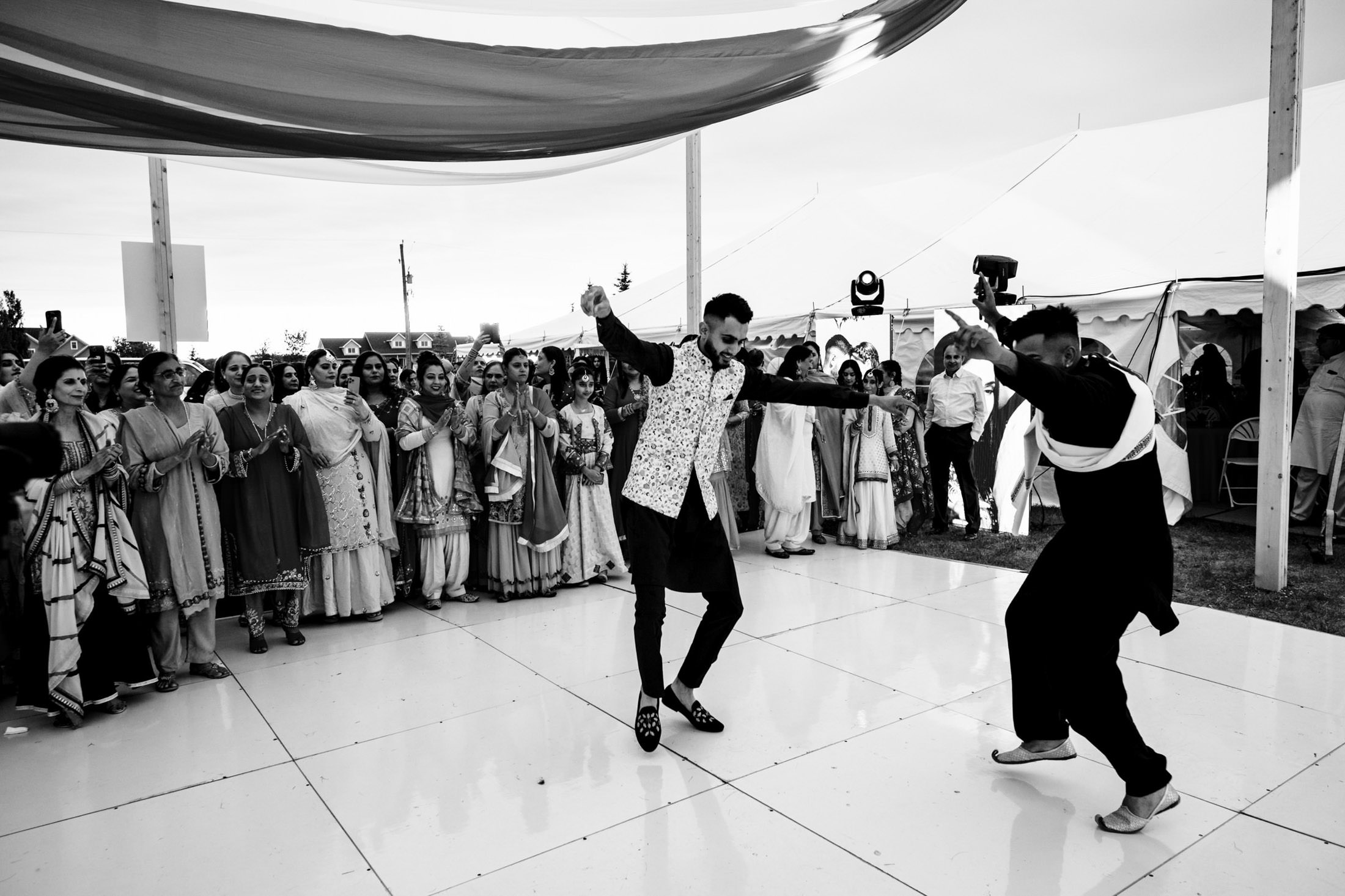 Two people dance energetically at an outdoor Winnipeg wedding as a crowd watches.