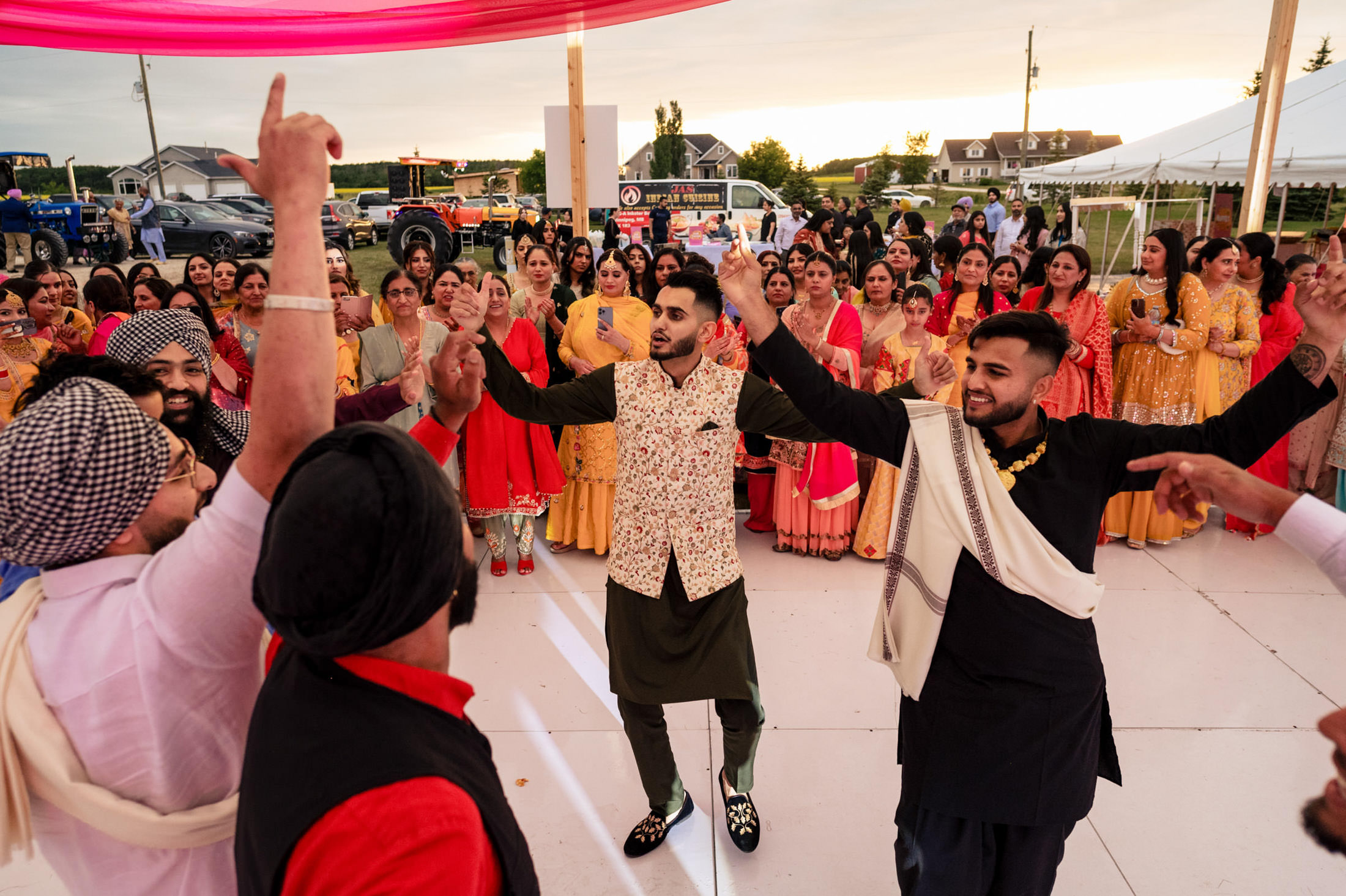 People dancing joyfully at a vibrant Winnipeg wedding with draped fabric overhead.