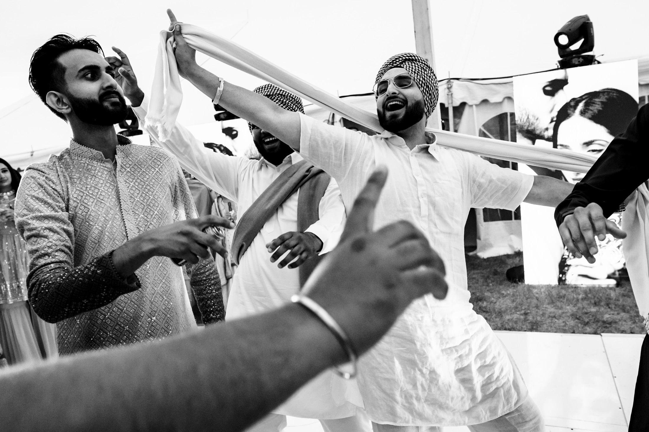 People joyfully dancing in traditional clothing at a Winnipeg wedding celebration.