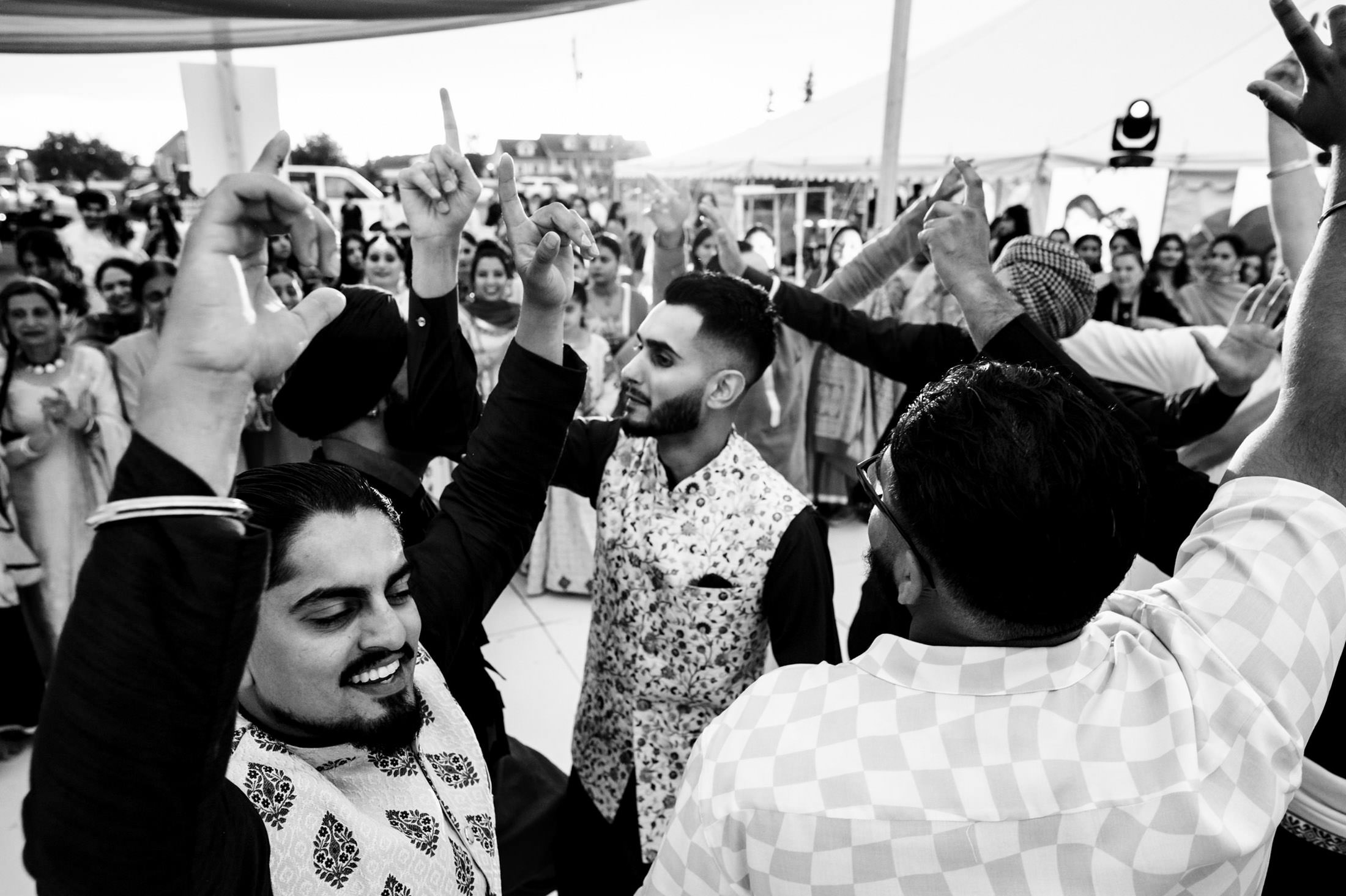 People dancing energetically outdoors at a festive Winnipeg wedding celebration.