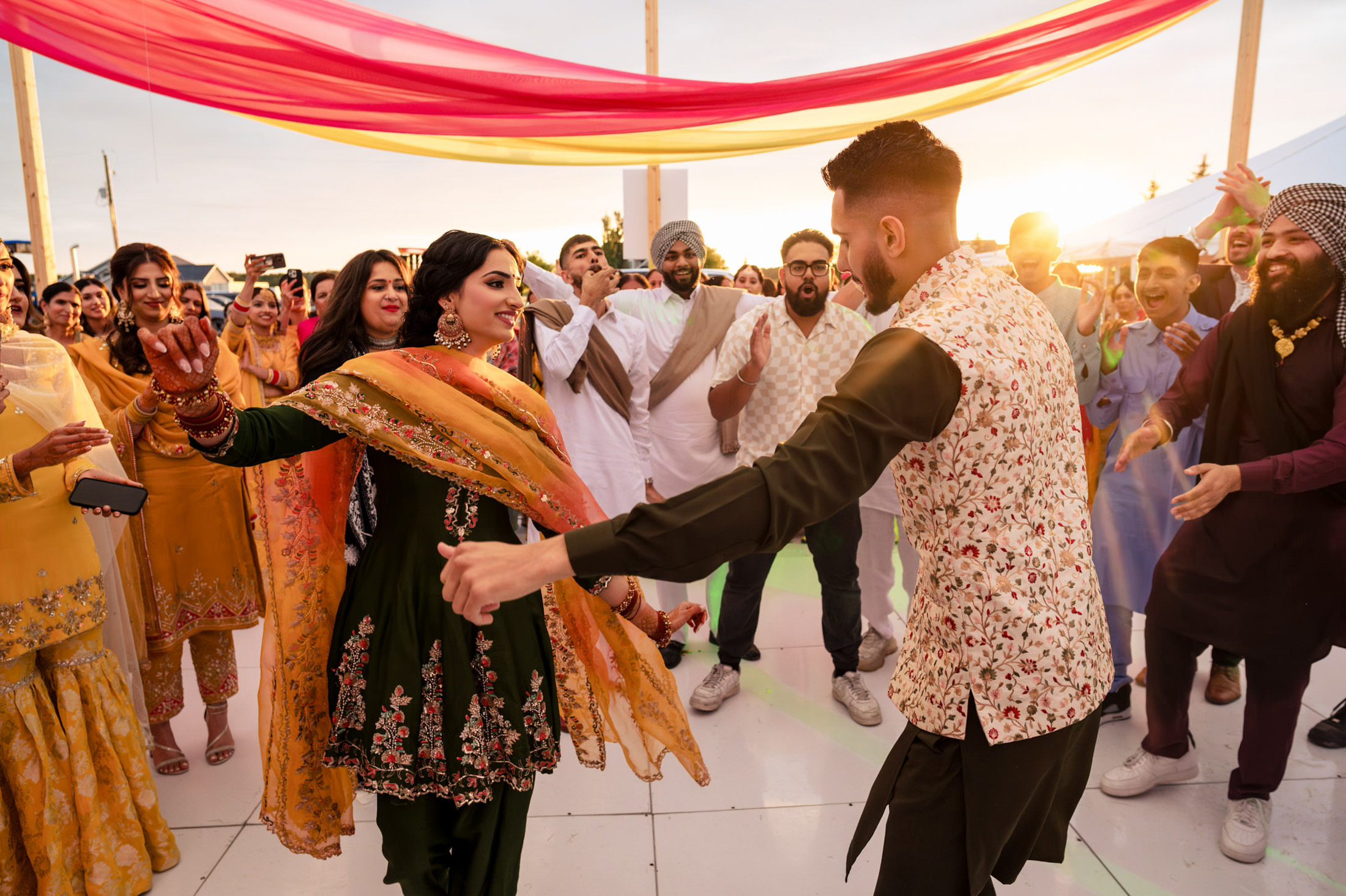 Joyful dancers at a festive Winnipeg wedding with colorful drapes overhead.