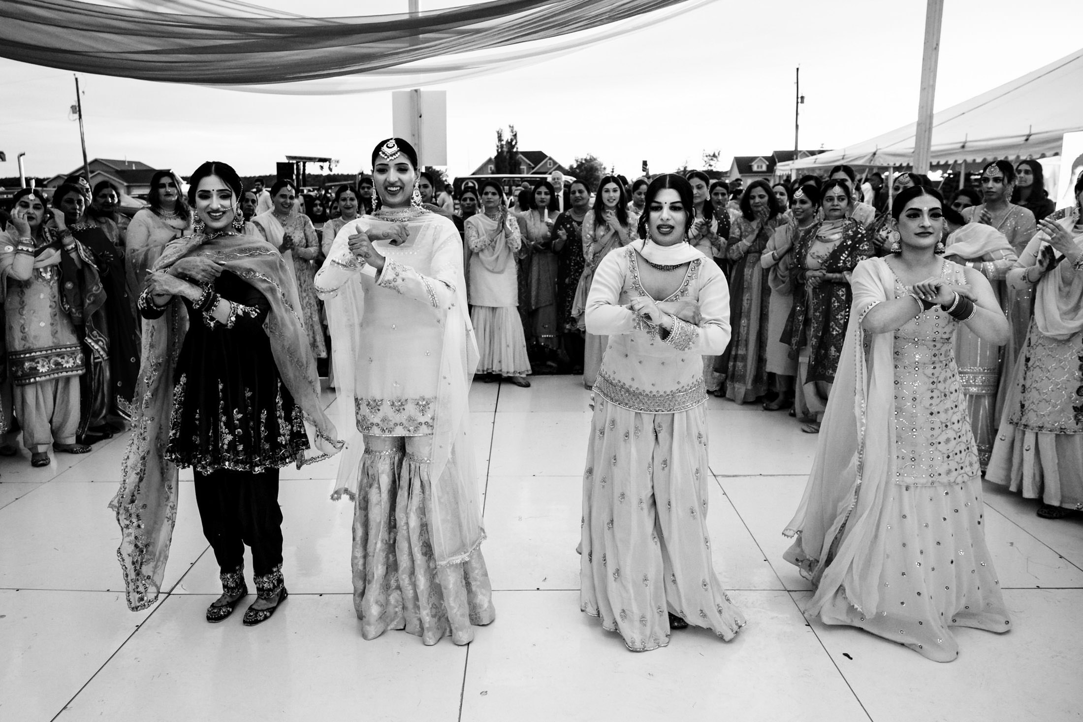 Four people dancing in traditional attire at a lively Winnipeg wedding celebration.