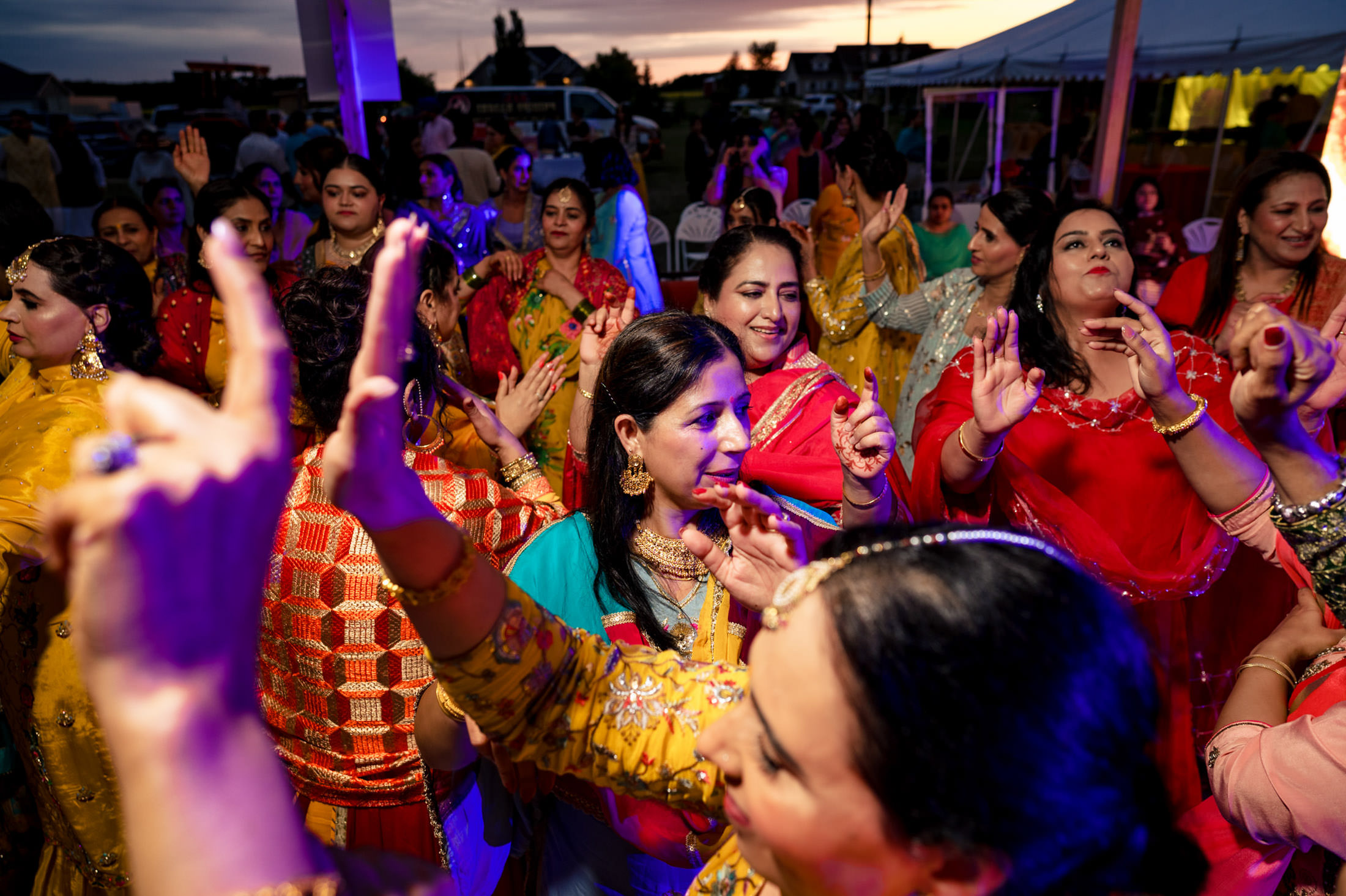 People joyfully dancing in colorful attire at a lively Winnipeg wedding celebration.