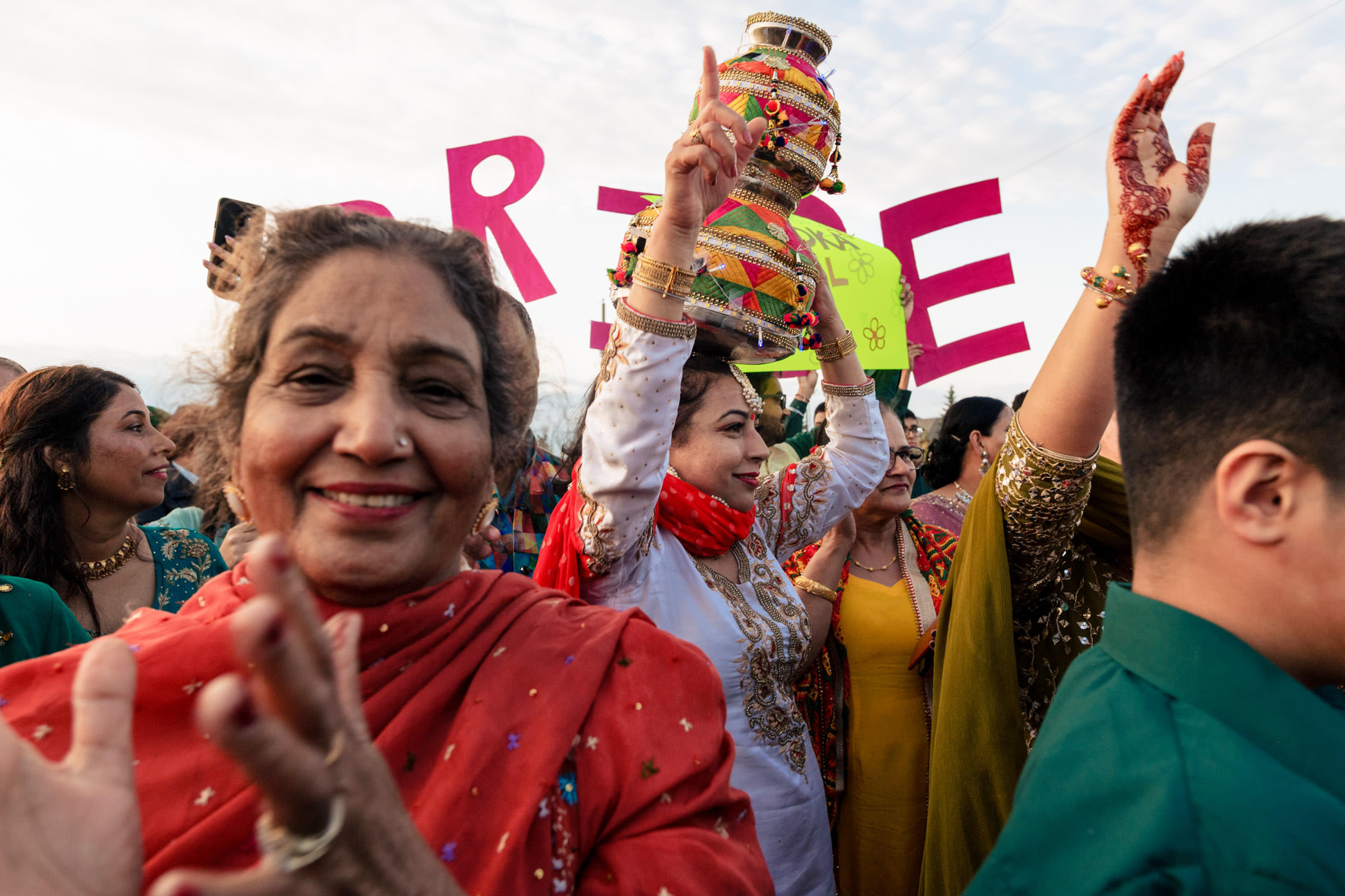Group celebrating in traditional attire at a Winnipeg wedding; woman holds decorated pot.