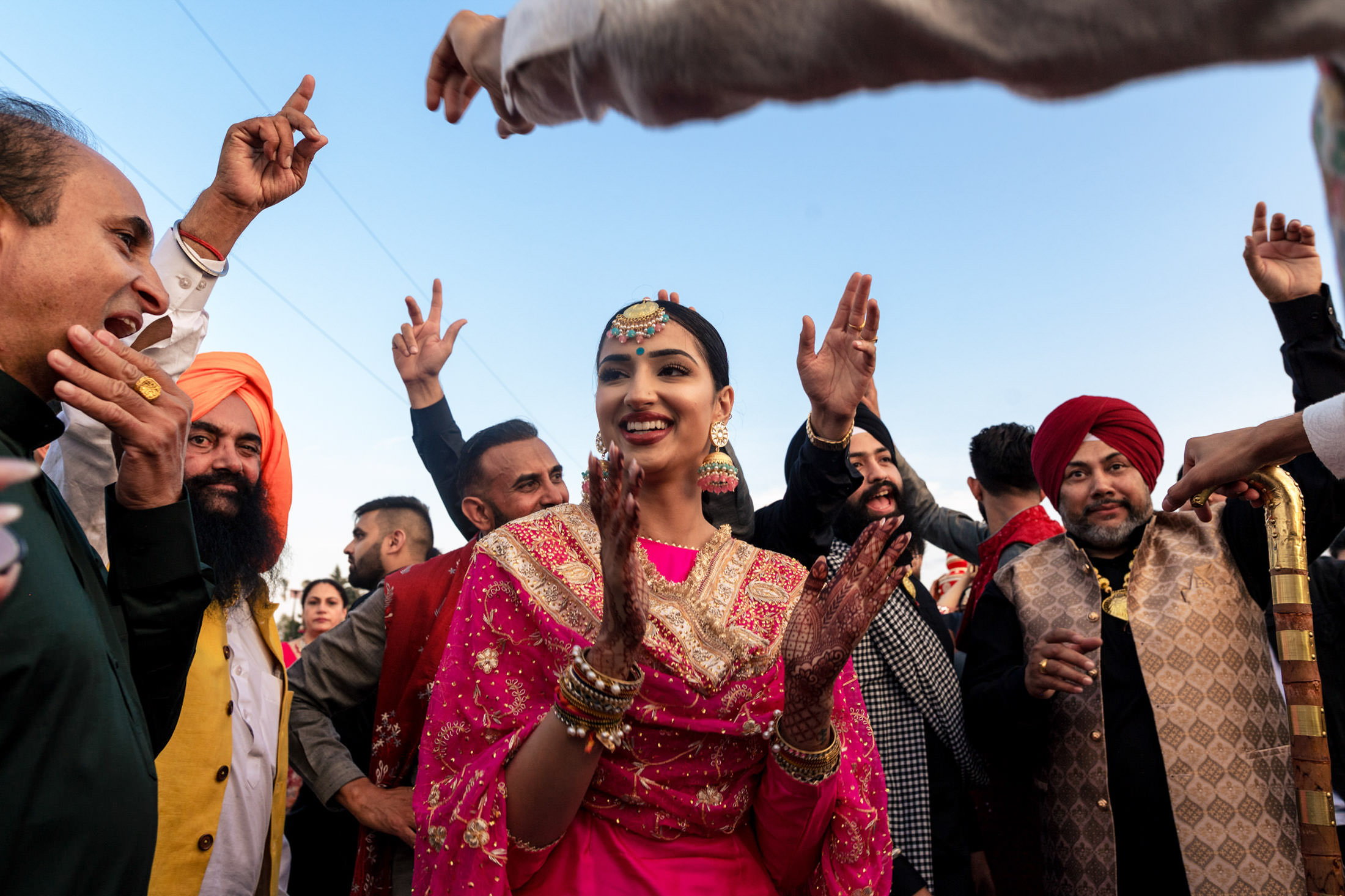 A joyful woman in traditional attire dances at a lively Winnipeg wedding celebration outdoors.