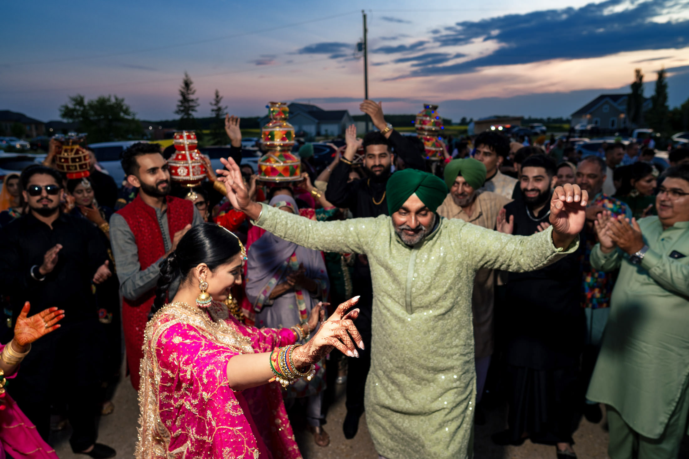 Joyful dancing at a Winnipeg wedding, with some in traditional attire, as the sun sets.
