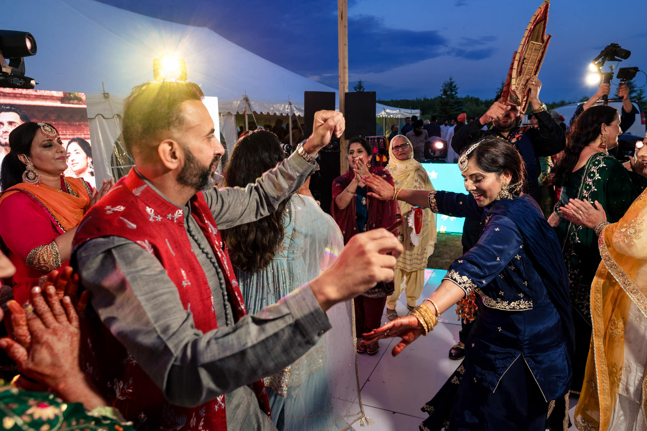 People dancing energetically at a lively Winnipeg wedding in colorful traditional attire.