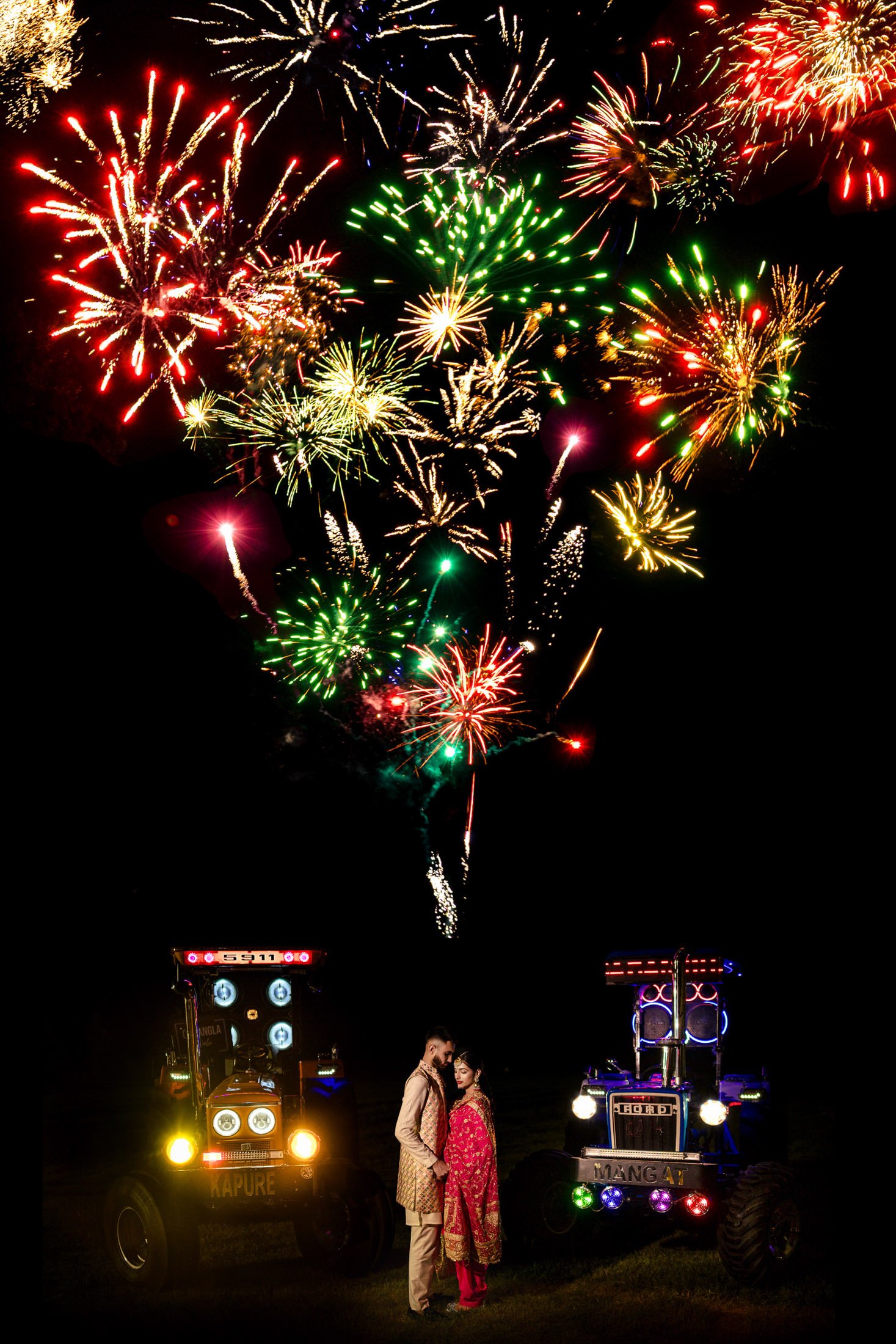 A couple in traditional attire stands amid tractors at a vibrant Winnipeg wedding fireworks display.
