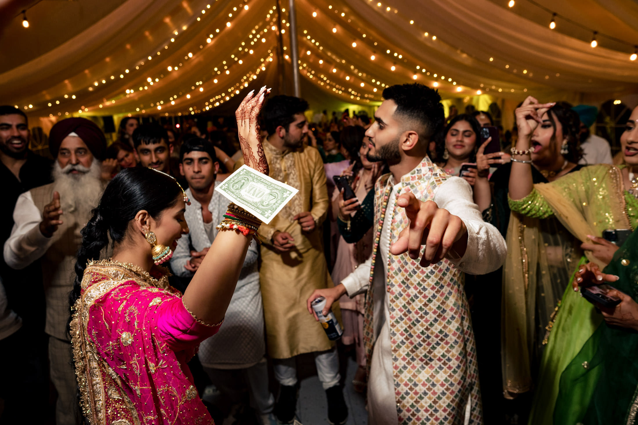 Guests dancing at a Winnipeg wedding under string lights in a beautifully decorated tent.