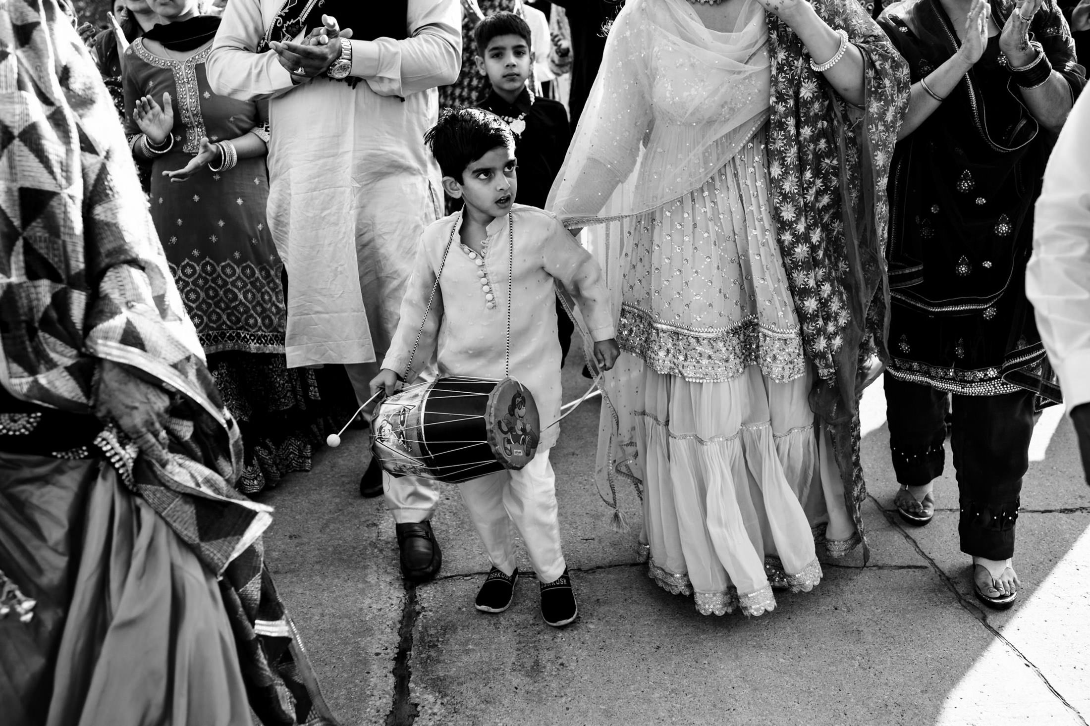 Child in traditional attire plays a drum at a lively Winnipeg wedding celebration.