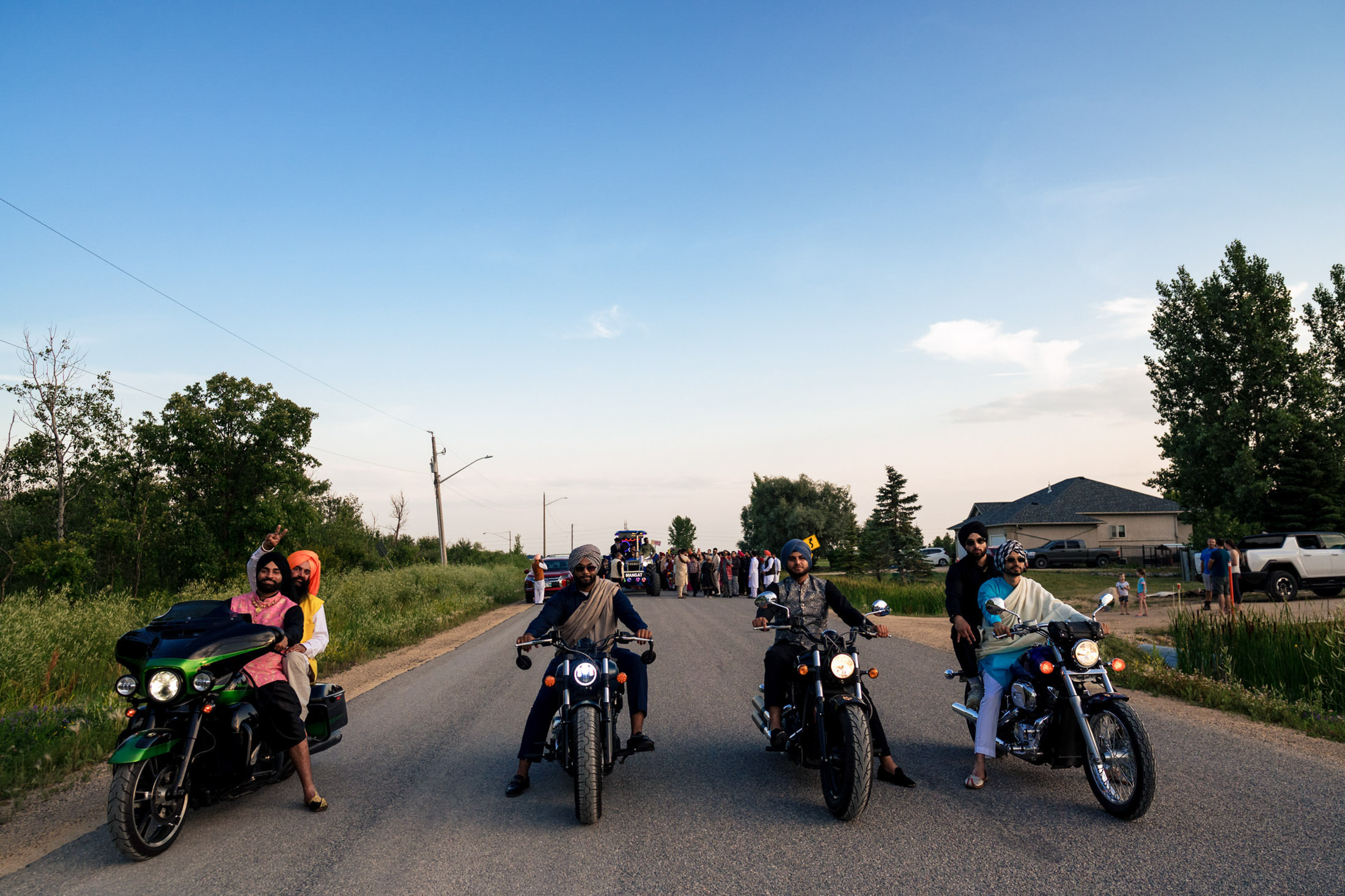 People on motorcycles, possibly a Winnipeg wedding, parked on road with crowd in background.