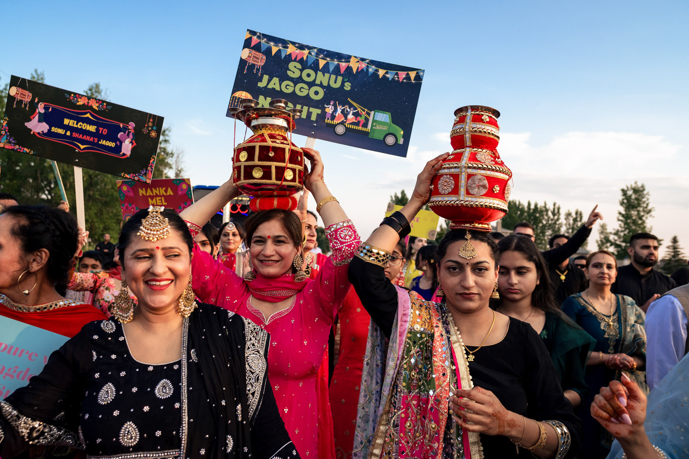Winnipeg wedding joy: people celebrating, holding colorful jars and signs in traditional attire.