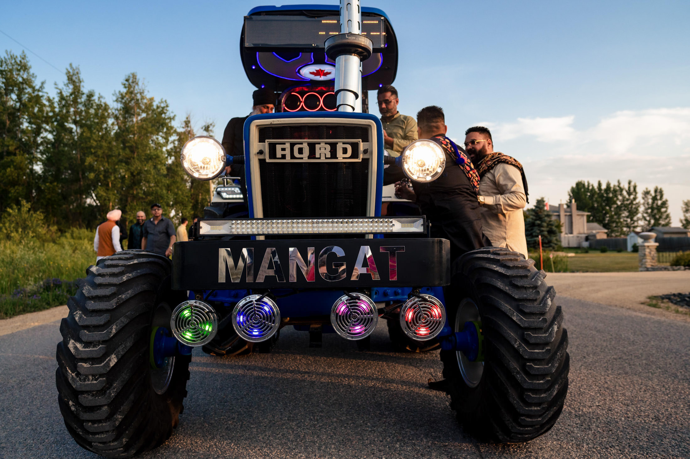 Modified Ford tractor with colorful lights at a Winnipeg wedding, surrounded by cheerful guests.