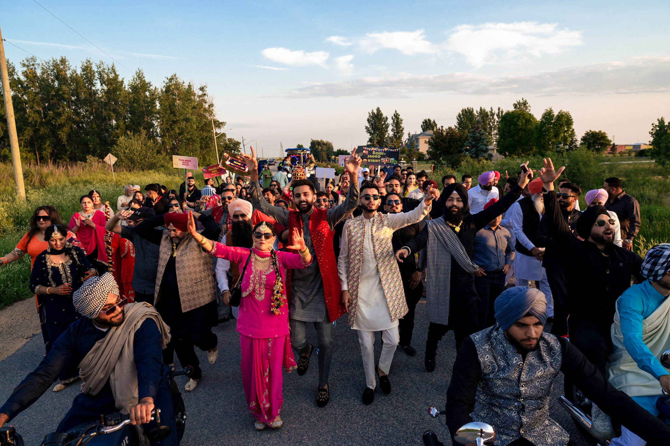 People in colorful traditional attire dancing on a rural road at a Winnipeg wedding.