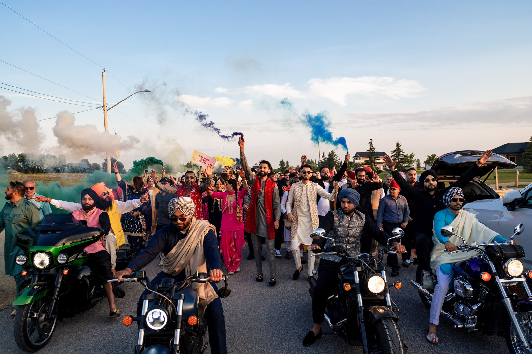 A vibrant group celebrates joyously with colorful smoke and motorcycles at a Winnipeg wedding.