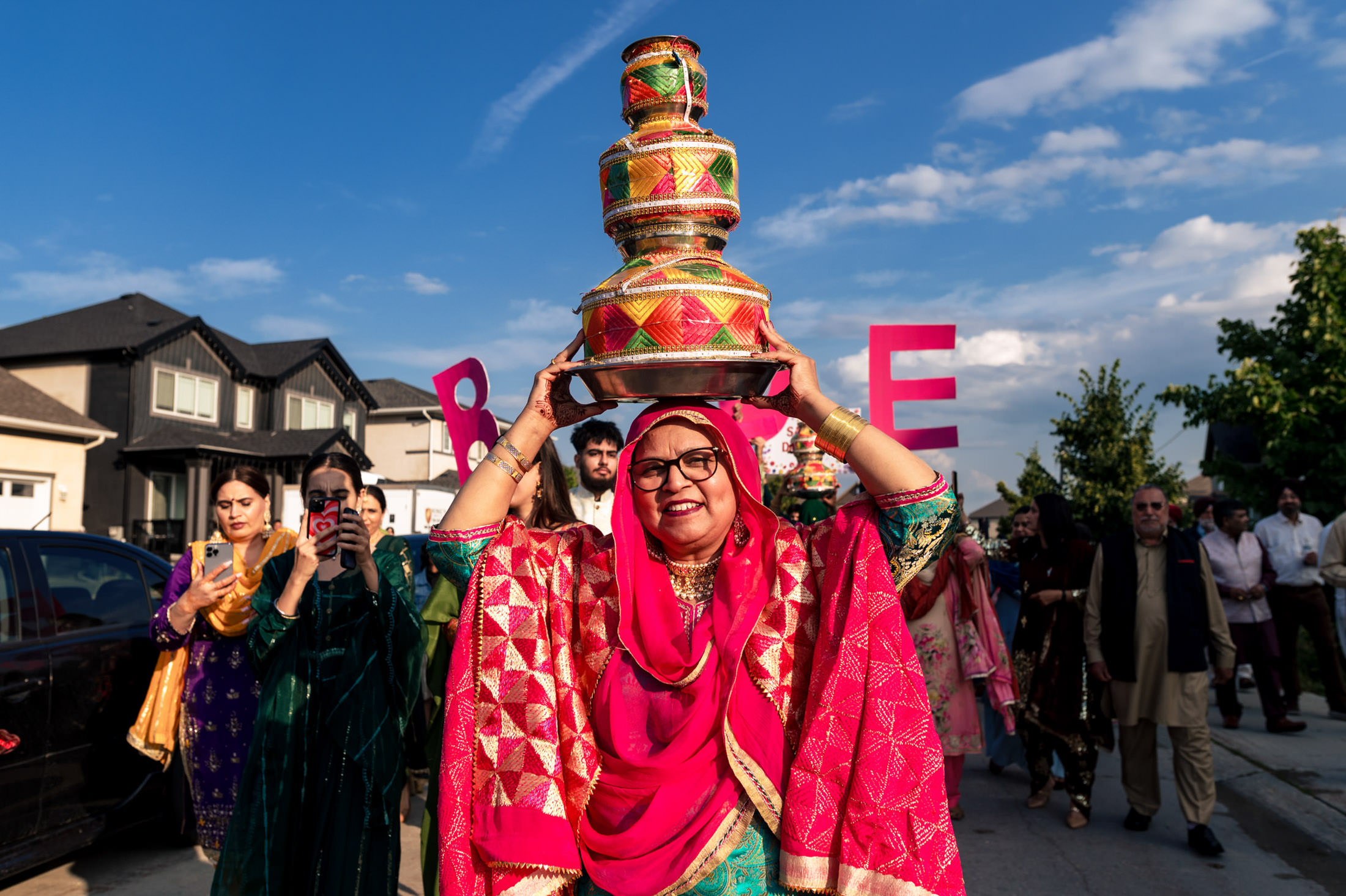Woman carrying a colorful pot on her head during a Winnipeg wedding celebration.