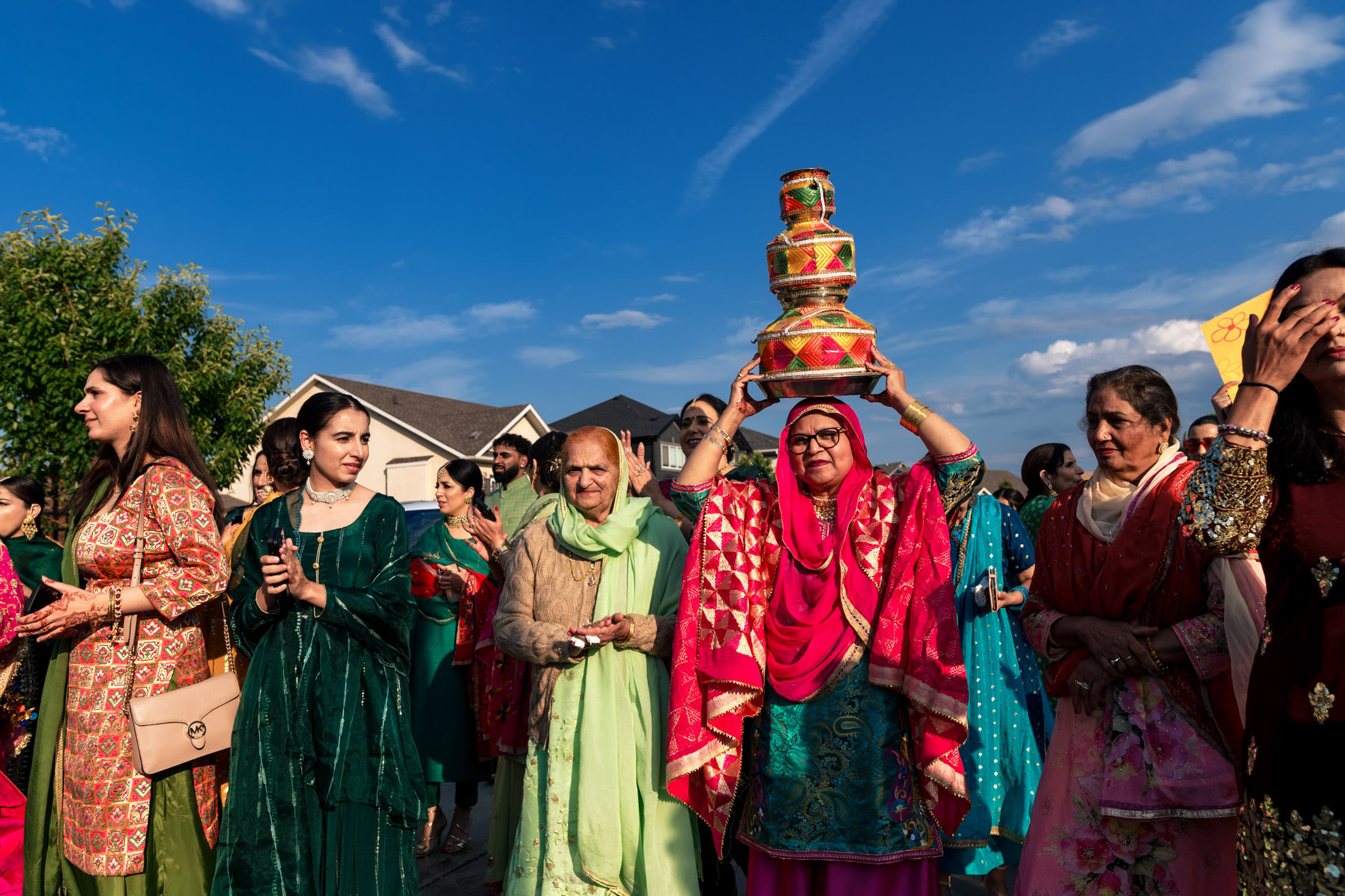 People in colorful traditional attire at a Winnipeg wedding under a clear blue sky.