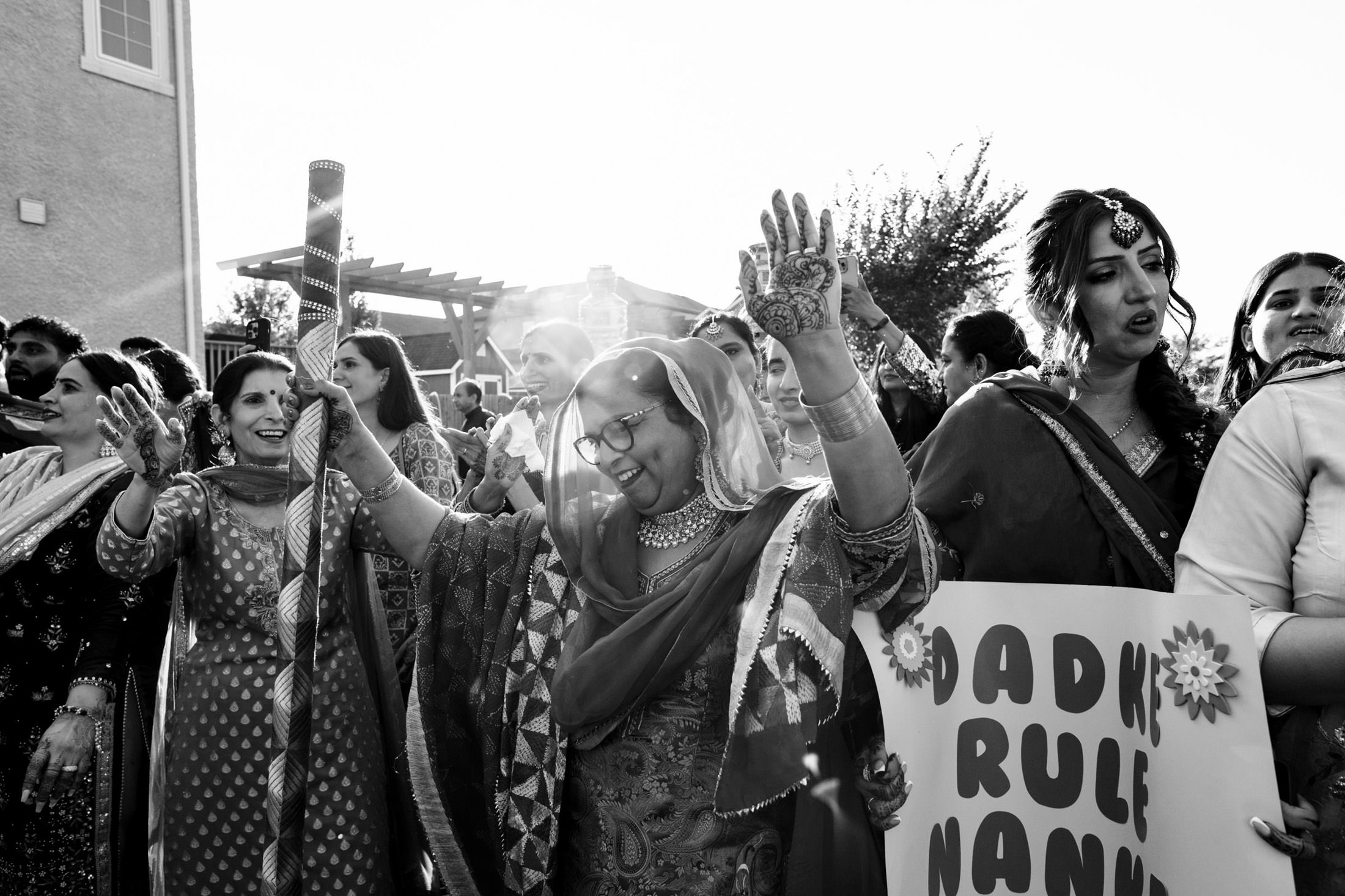 A joyful group celebrates at a Winnipeg wedding with dancing and signs outdoors.