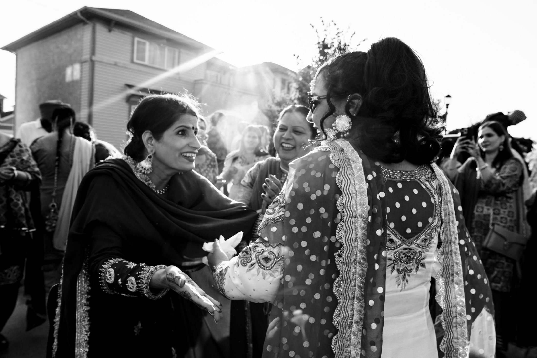 Women in traditional attire joyfully celebrate outdoors at a lively Winnipeg wedding.