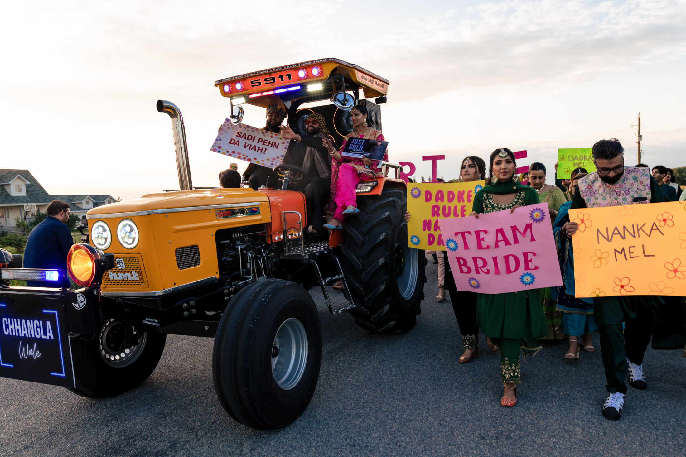 Winnipeg wedding joy with a decorated tractor, colorful signs, and festive attire.