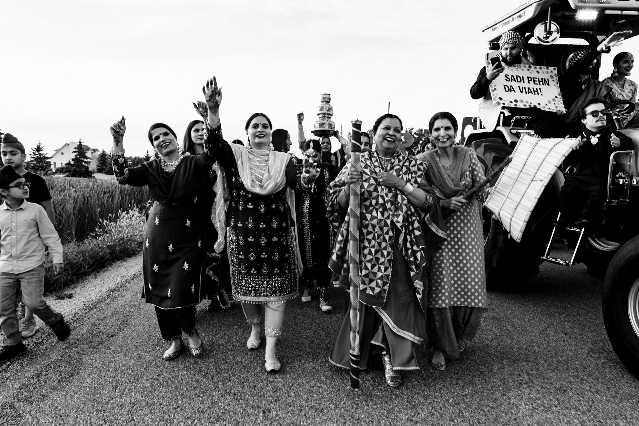 A joyful group dances in celebration by a tractor on a rural Winnipeg wedding road.