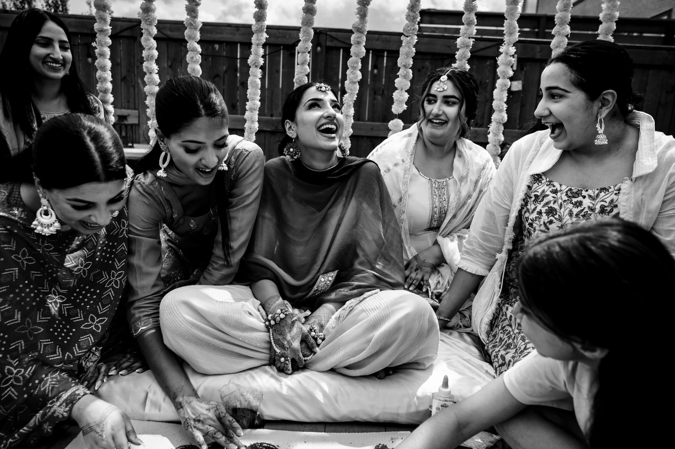 Women sitting and laughing together during a festive Winnipeg wedding celebration.