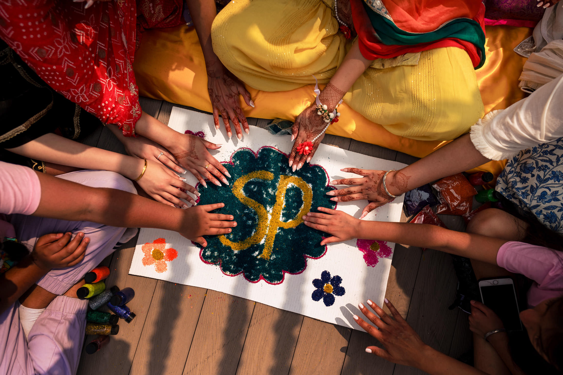 People decorating a colorful canvas design with hands during a Winnipeg wedding celebration.