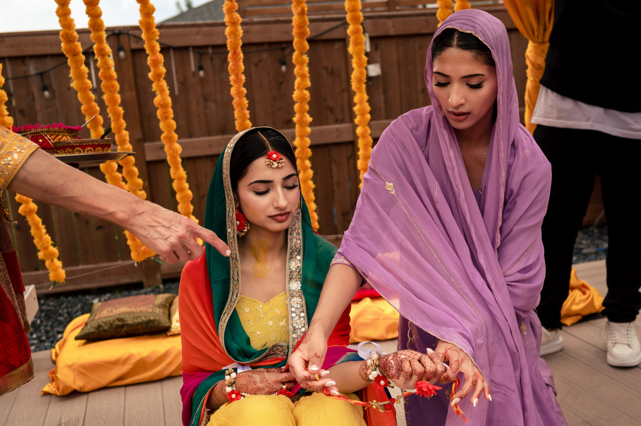Two women in traditional attire celebrate a Winnipeg wedding with marigolds in the background.