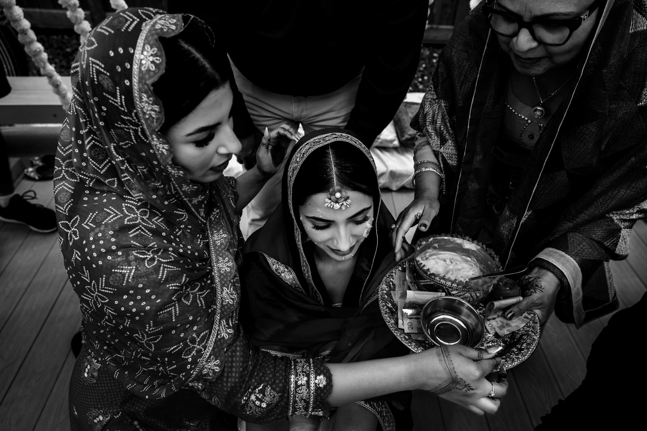 Women in decorated shawls perform a ceremony, offering trays as at a Winnipeg wedding.