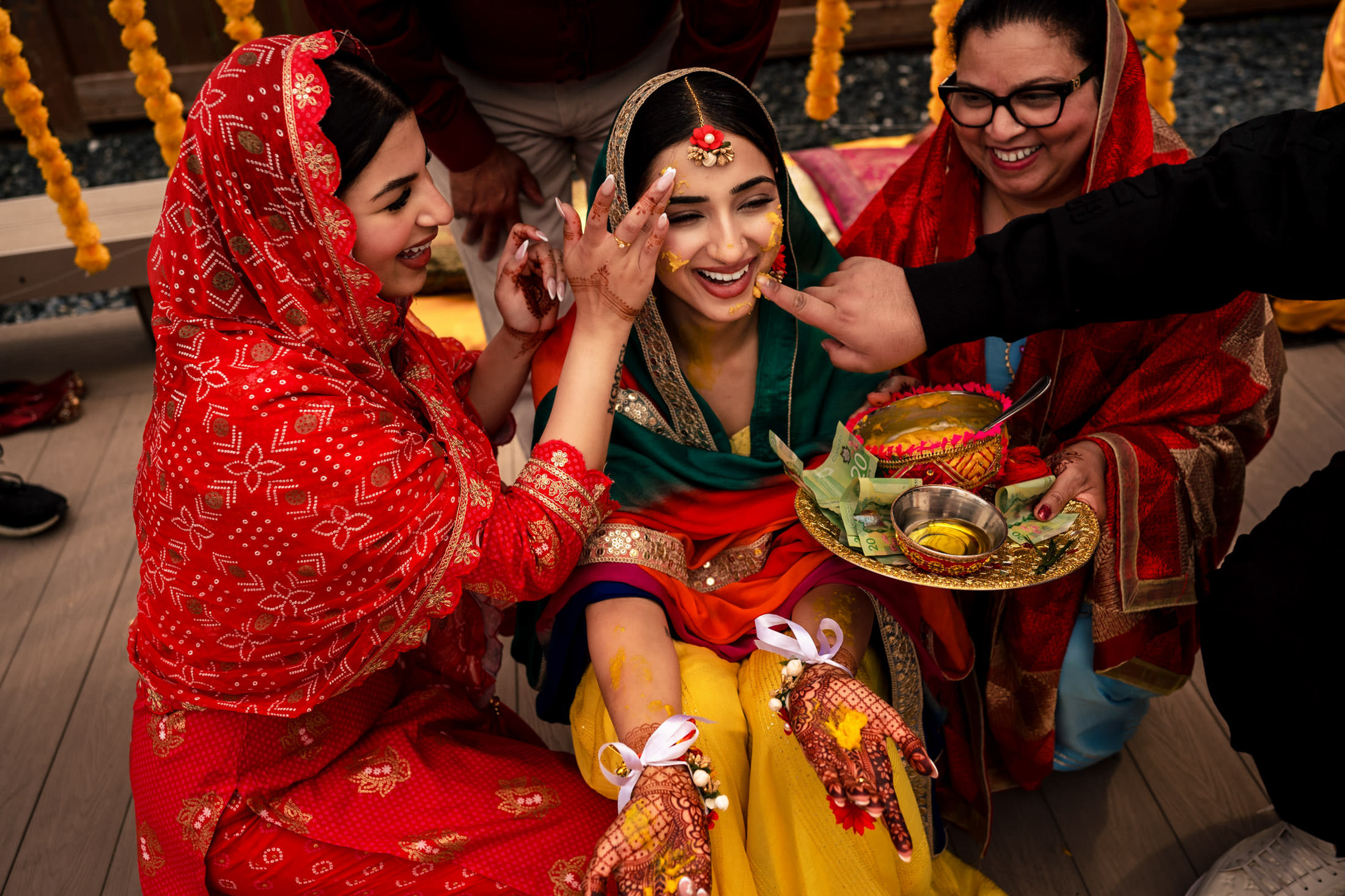 Bride at a Winnipeg wedding, surrounded by joyful women in colorful attire.