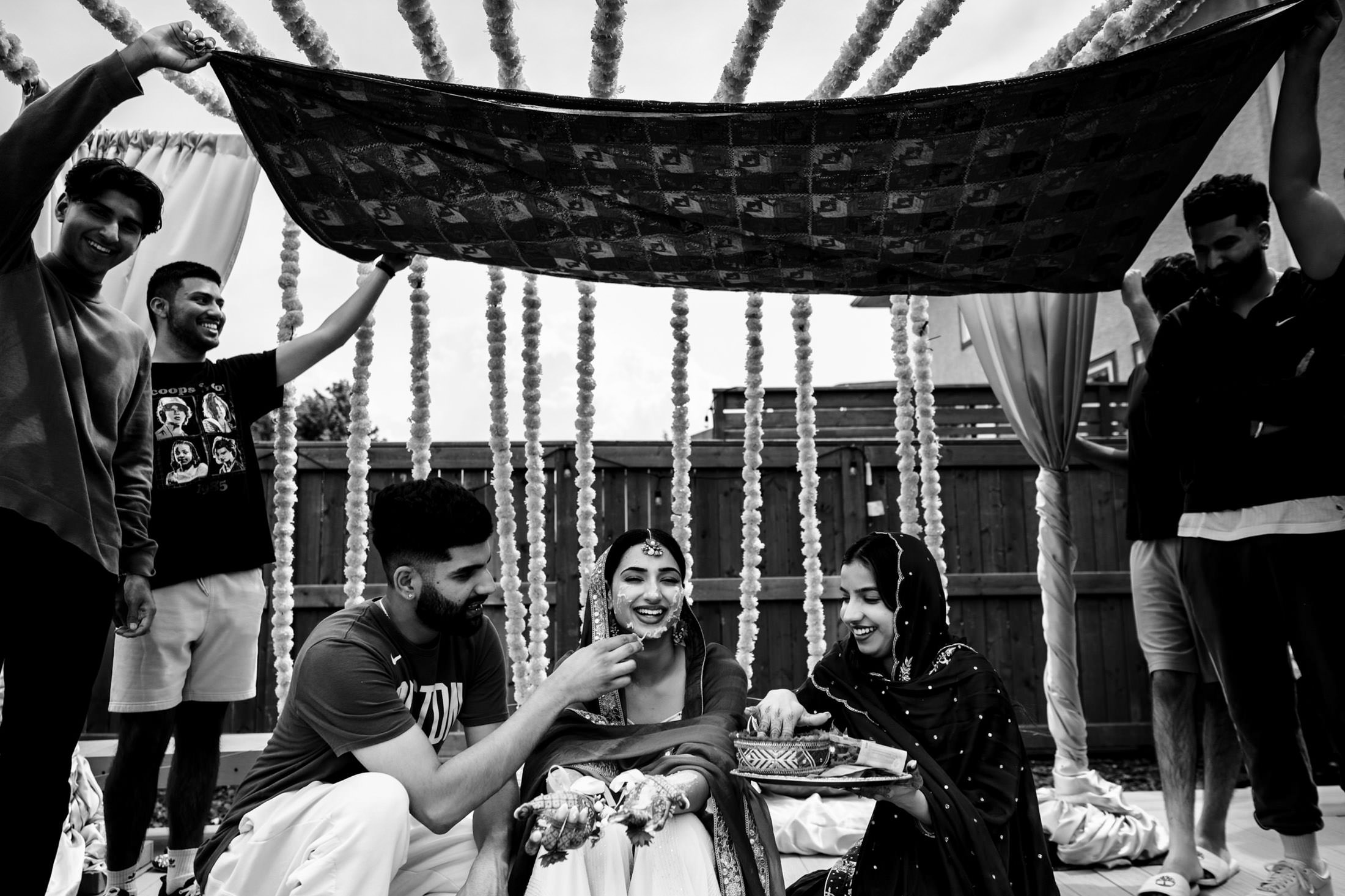 People gather under decorated canopy at a Winnipeg wedding, sharing food and laughs.