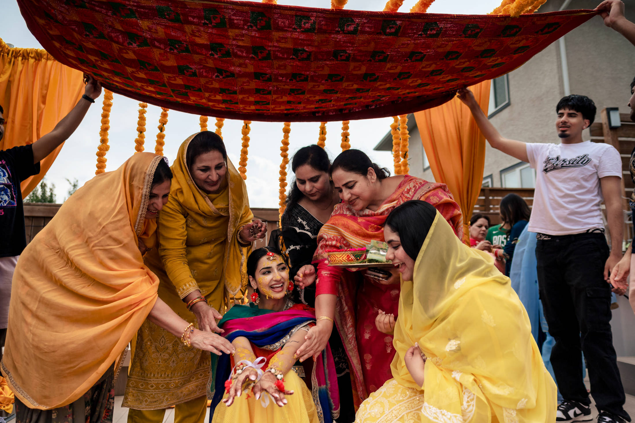 A woman in traditional attire at a vibrant Winnipeg wedding, surrounded by smiling women.