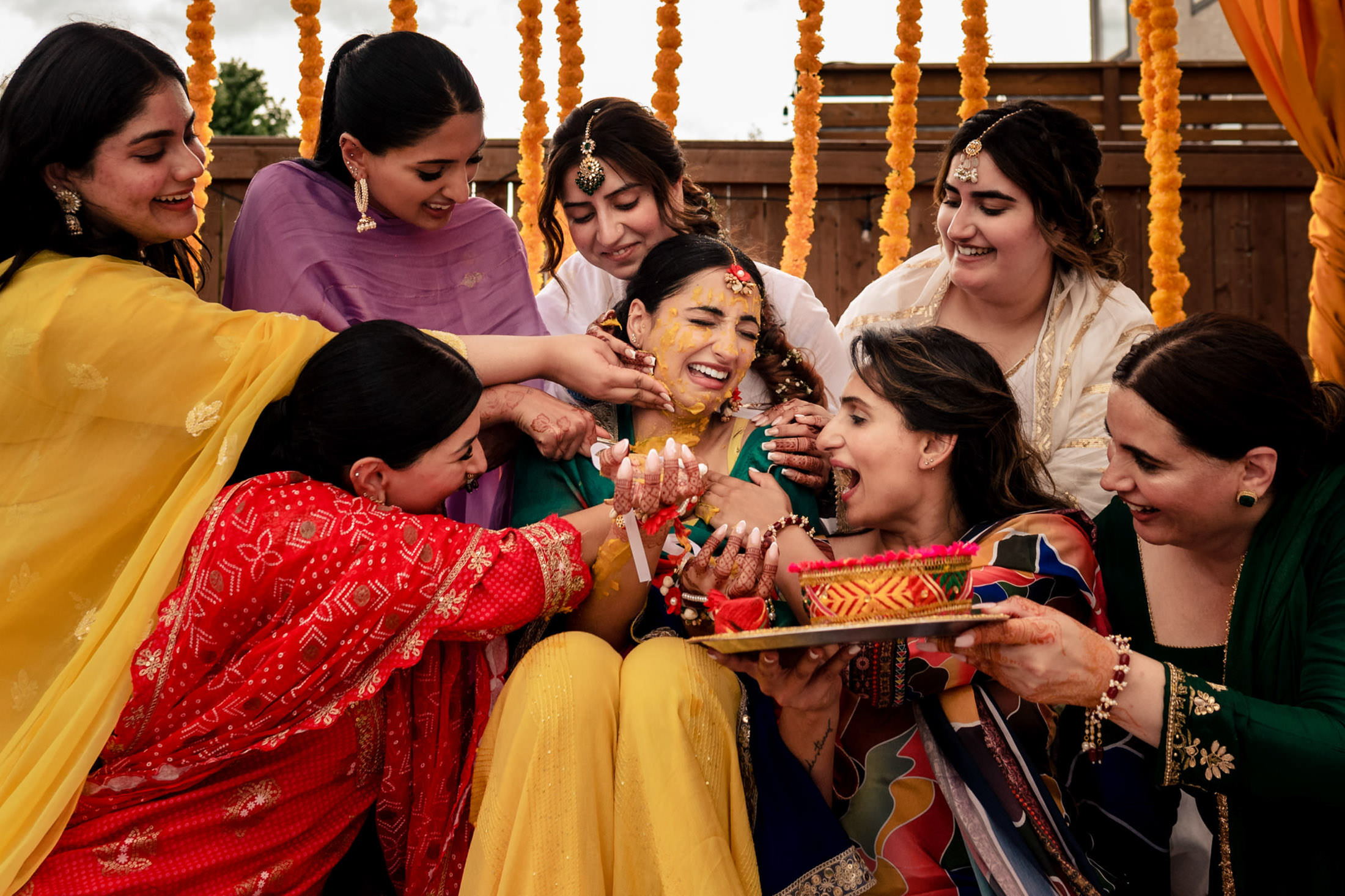 Women in Winnipeg joyfully celebrating a pre-wedding ceremony with vibrant colors and florals.